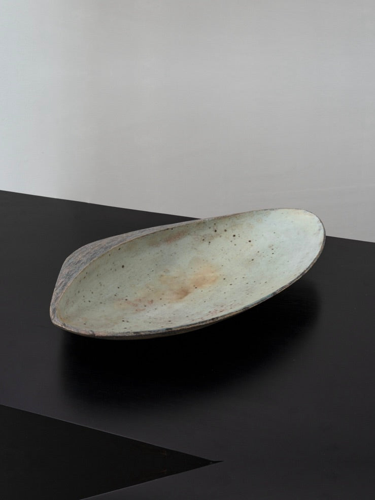 Large postmodern ceramic bowl with speckled glaze on dark surface