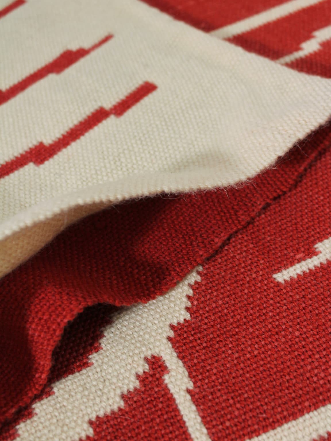 A close-up of the Vintage Stories Red Wool Wall Tapestry With Abstract Nature Motifs (72x180cm), showing its detailed red and cream patterns layered for a textured, vintage-inspired design.