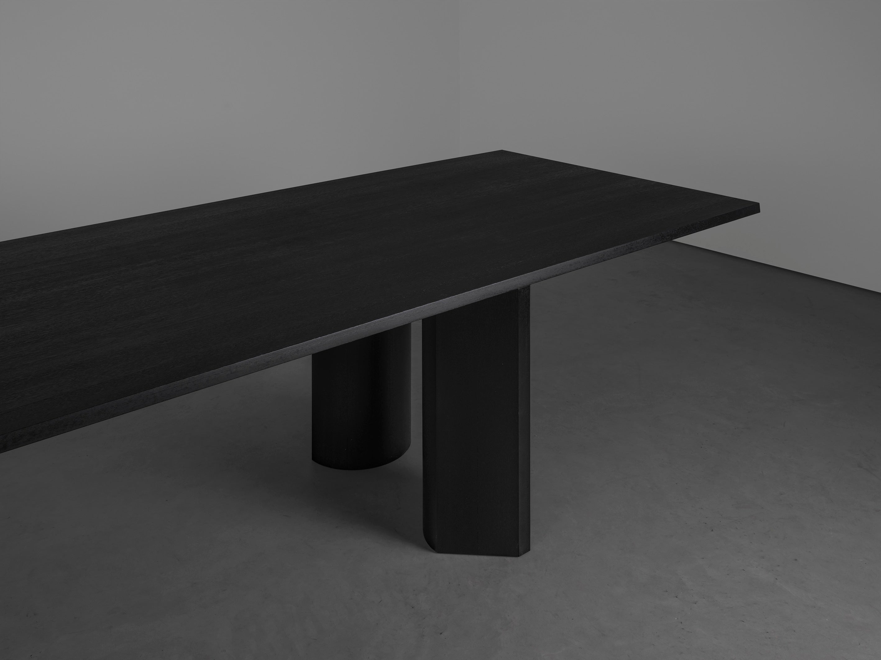 Corps - Dining Table — side angle showing dark wood surface and cylindrical legs