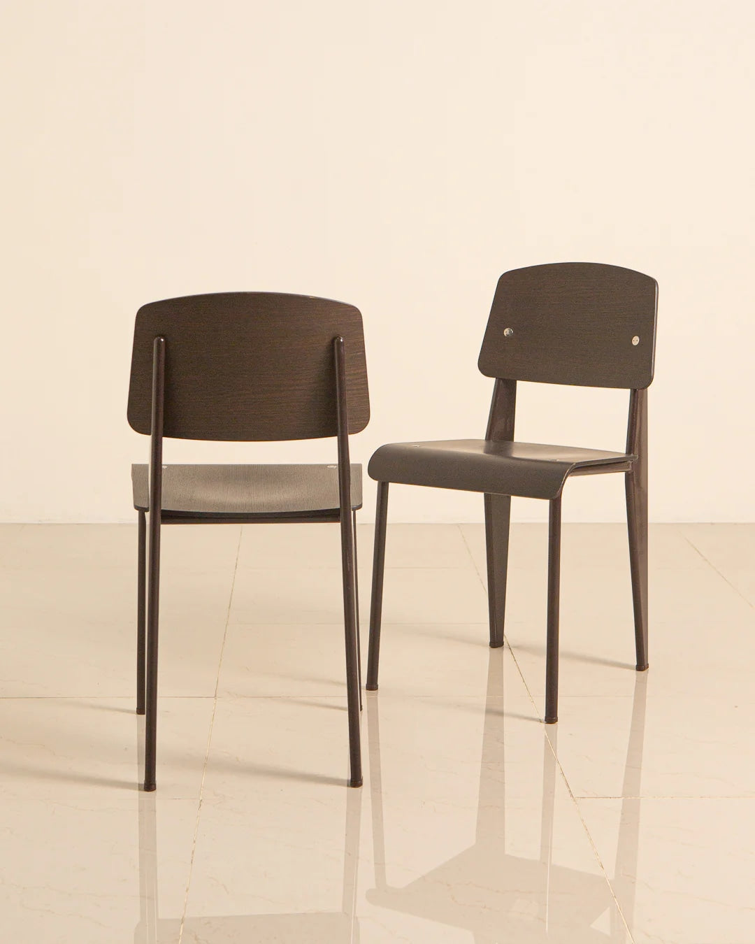 Two Jean Prouvé Standard chairs in dark wood showing profile view