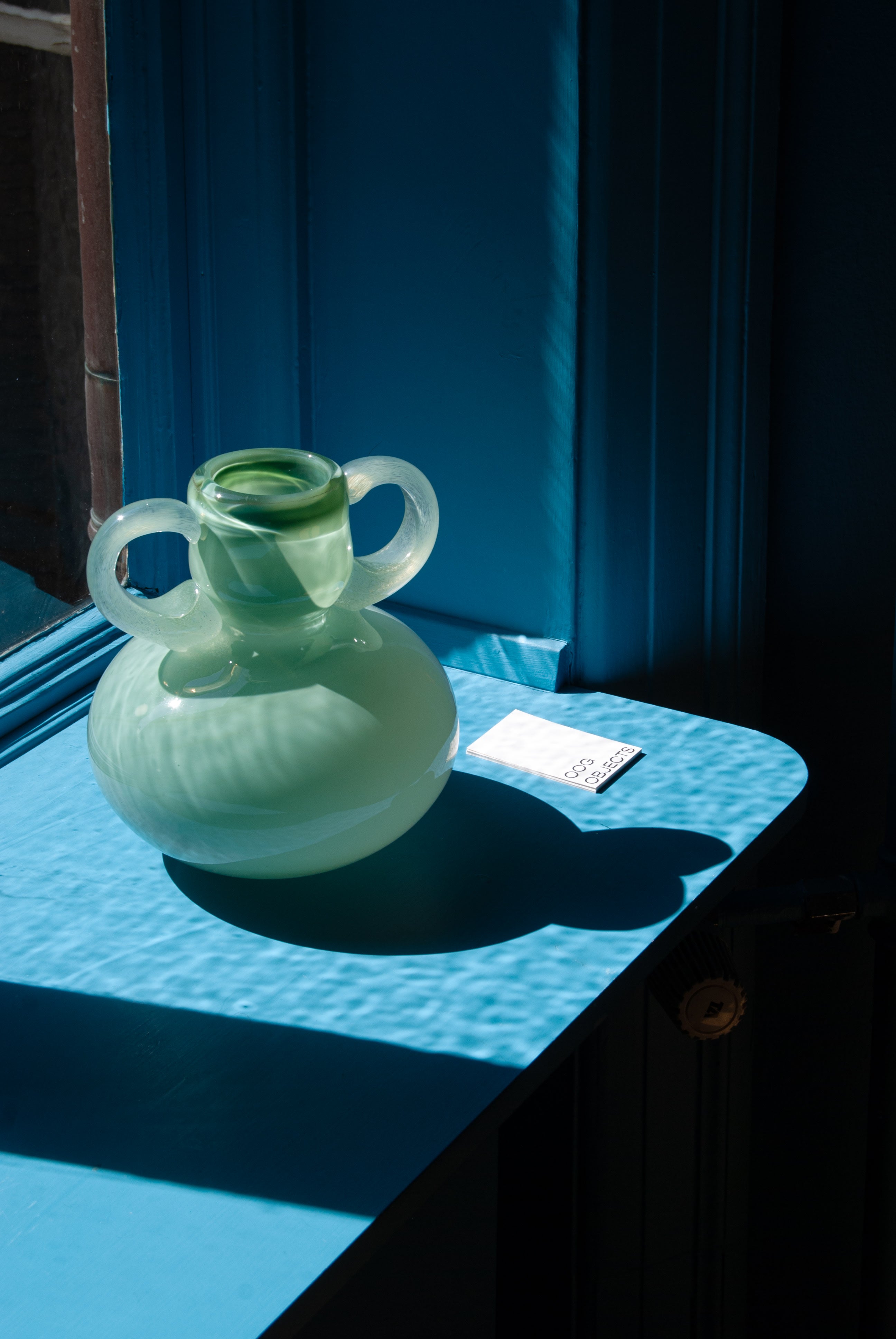 The Vase 03 — side angle on blue table with sunlight