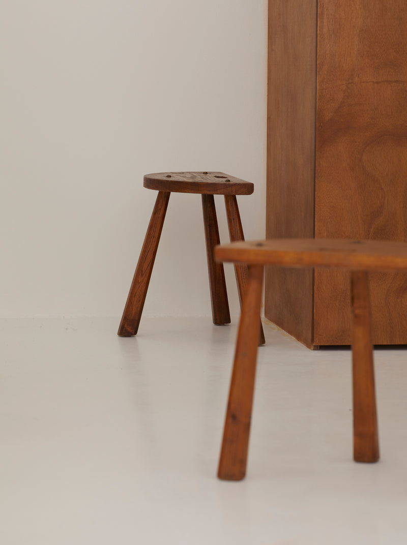 Two French Artisanal Solid Wood Half-moon Tripod Stools, Circa 1950 — angled view highlighting wooden legs and seat texture