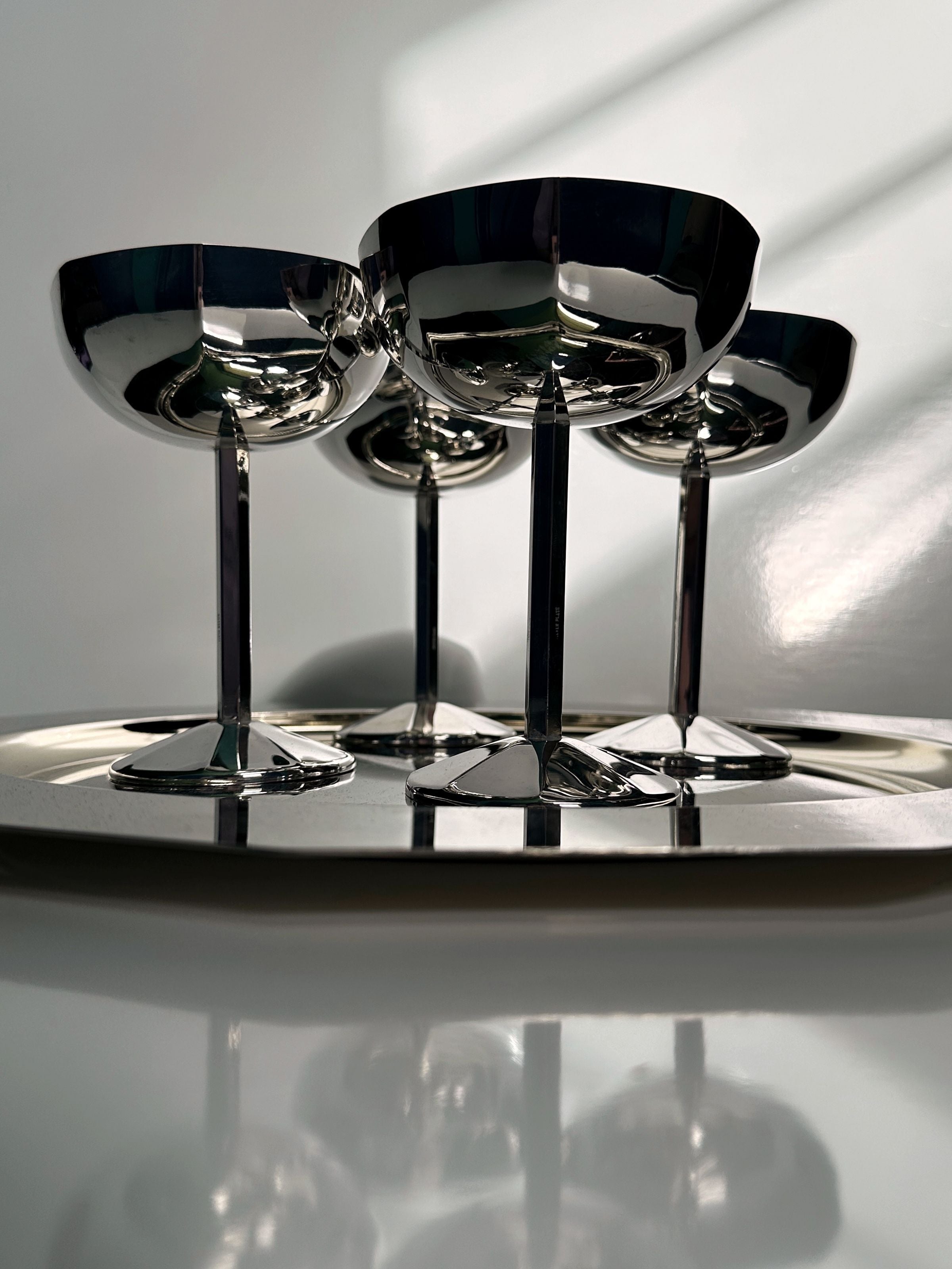 Four silver-plated Art Deco coupes with reflective surfaces on tray
