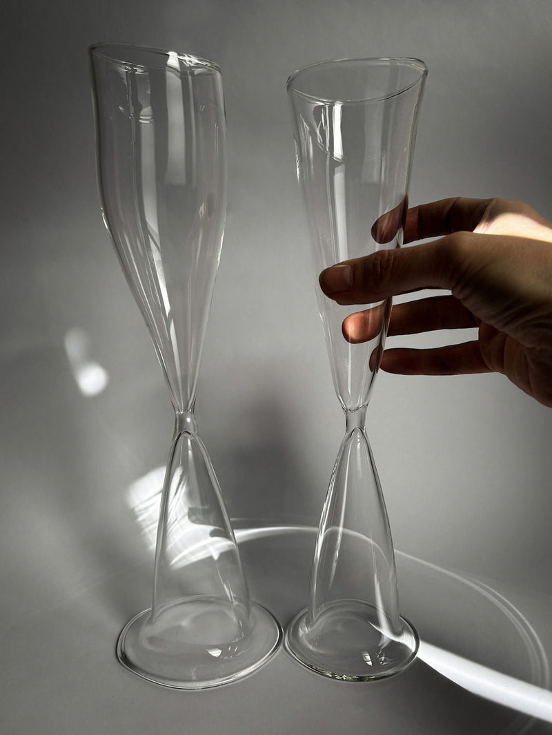Hand holding elegant glass champagne flute from crystal wine glass set