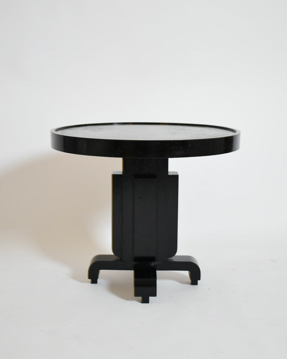 The Barracuda Interiors Round Ebonised Art Deco Geometric Side Table, 1930s, features a thick tabletop, geometric central support, and four short curved legs, showcased against a plain white background.