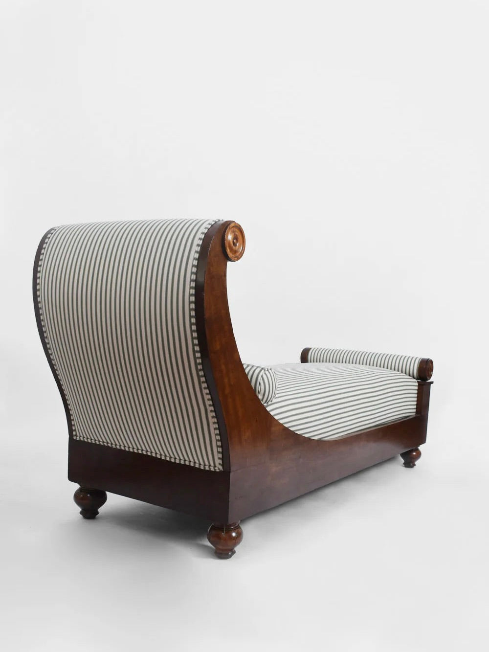 The Neoclassical Daybed, 19th Century by Barracuda Interiors features black and white striped upholstery, rolled arms, a scrolled headrest, and turned bun feet, shown against a plain white background.