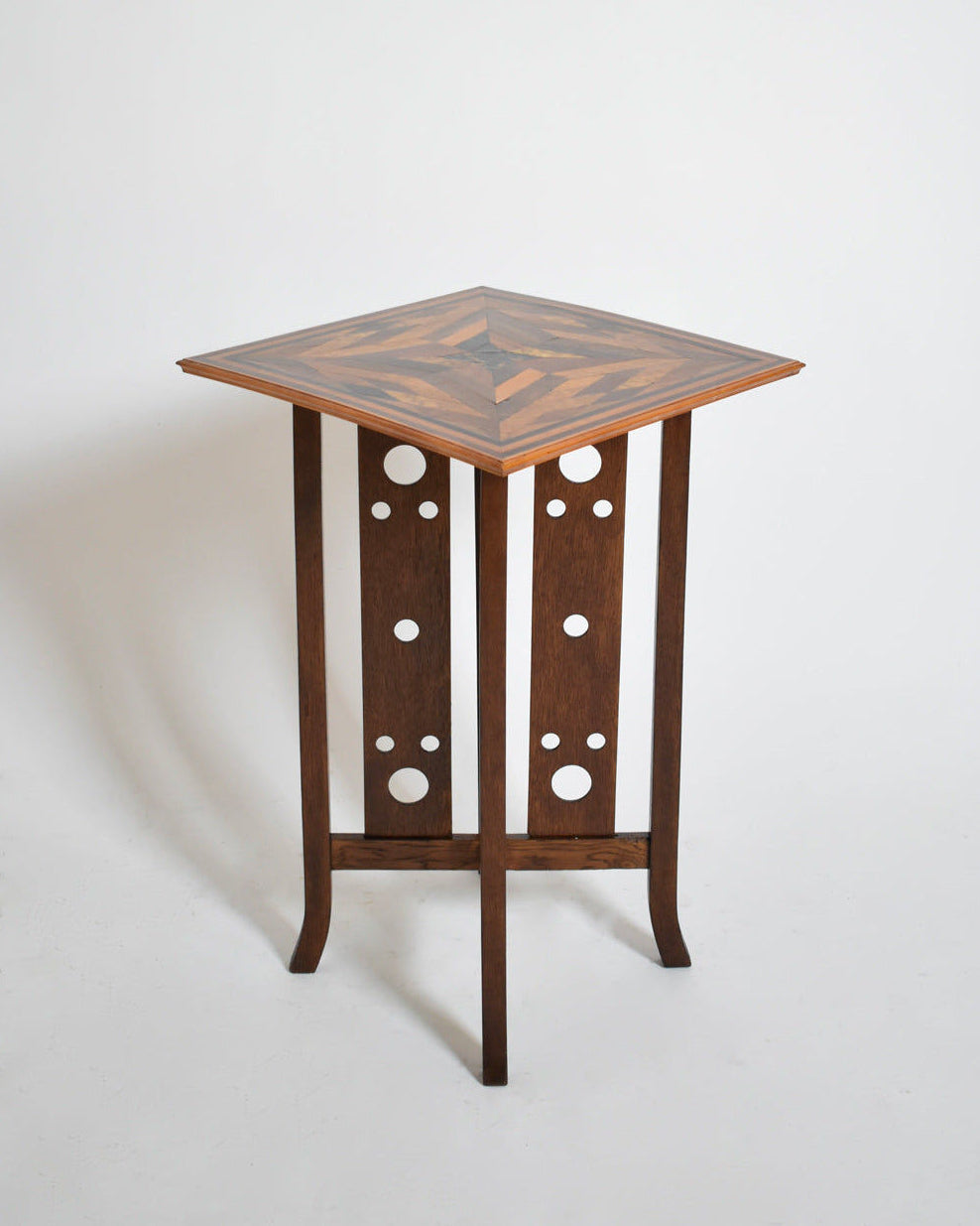 The Geometric Marquetry Side Table by Barracuda Interiors, 1920s, features a square inlaid top and three vertical legs with circular cut-out patterns, presented against a plain white background.