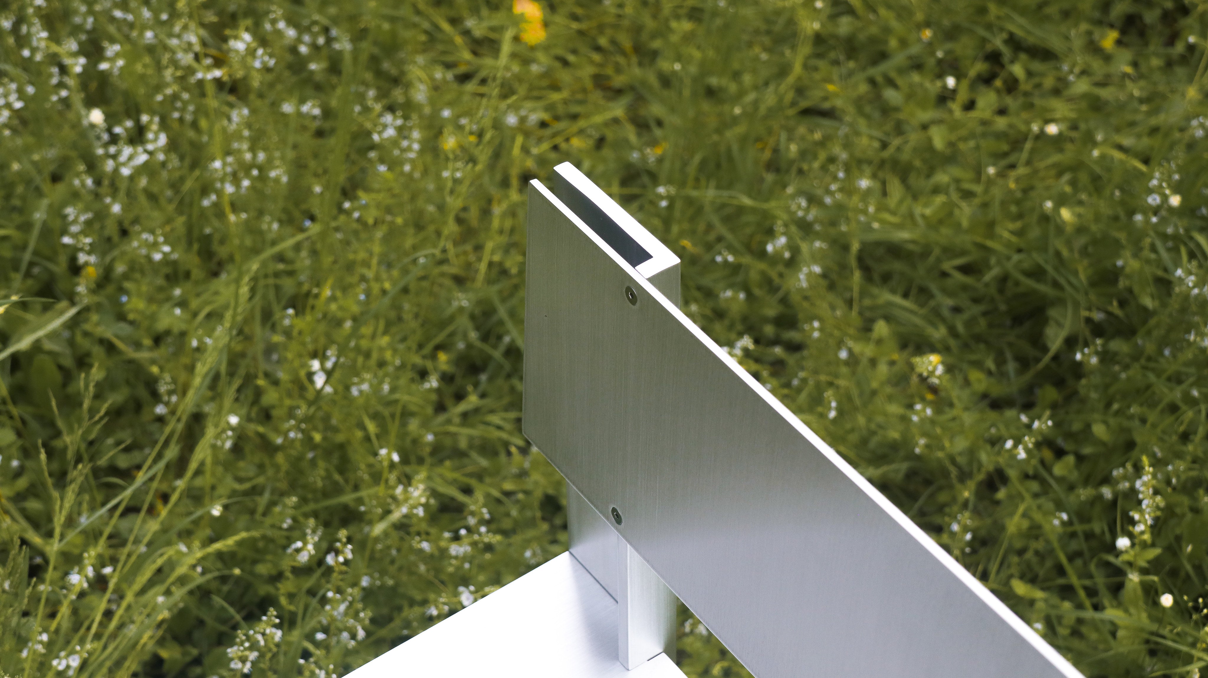 AL Chair — close-up of brushed aluminum armrest in grassy setting