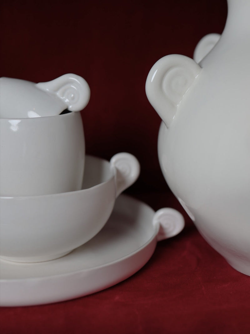 White ceramic plate with horn-shaped handles, teapot detail view