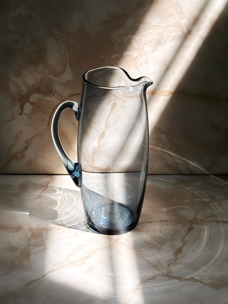 Clear glass Scandinavian carafe on marble surface with natural lighting