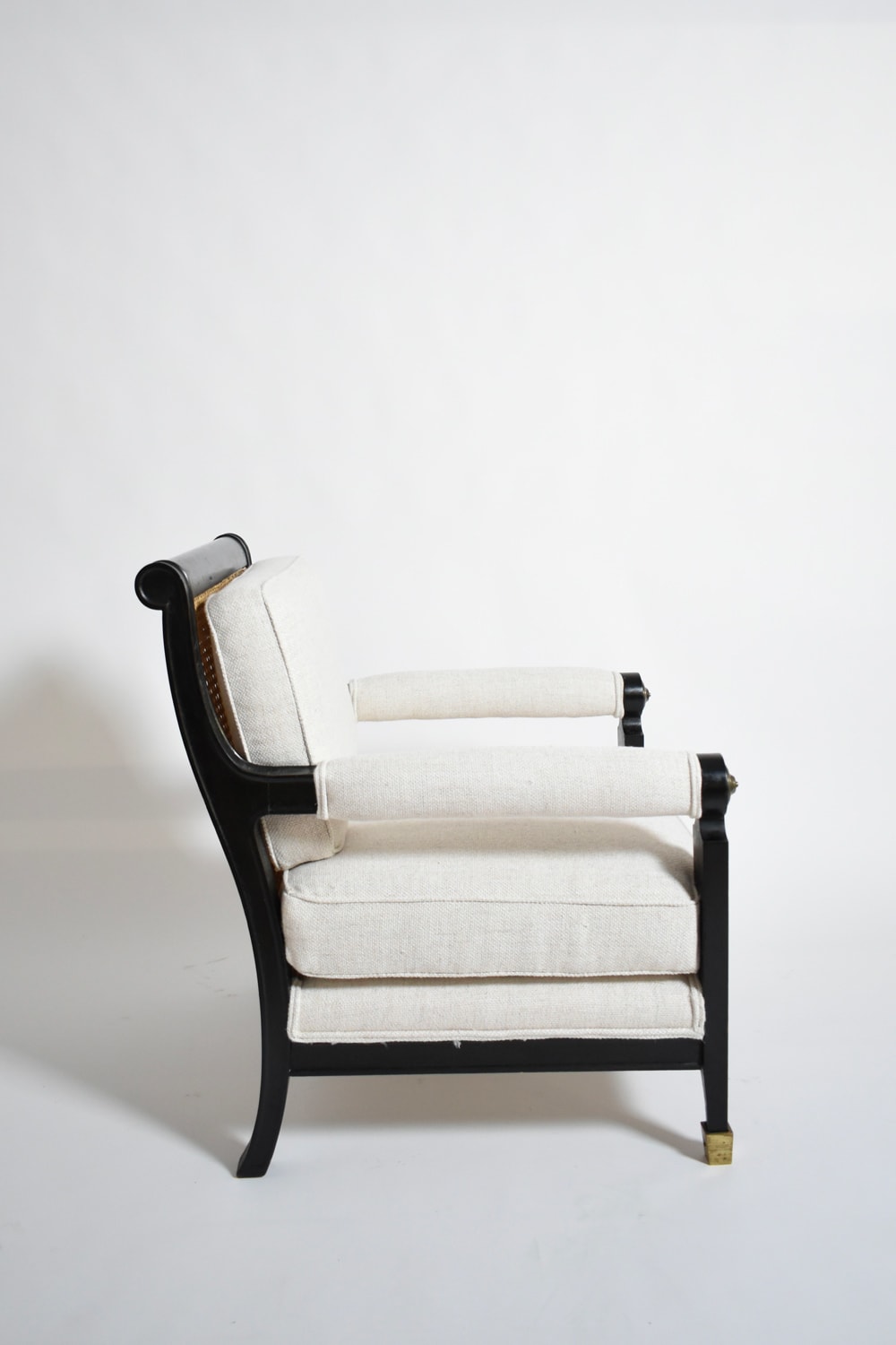 Pair of neoclassical ebonised wood and caning armchairs, 1960s — side profile with light fabric upholstery