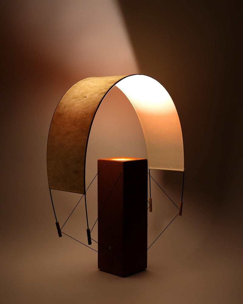 Modern terracotta table lamp with curved arch shade and warm glow