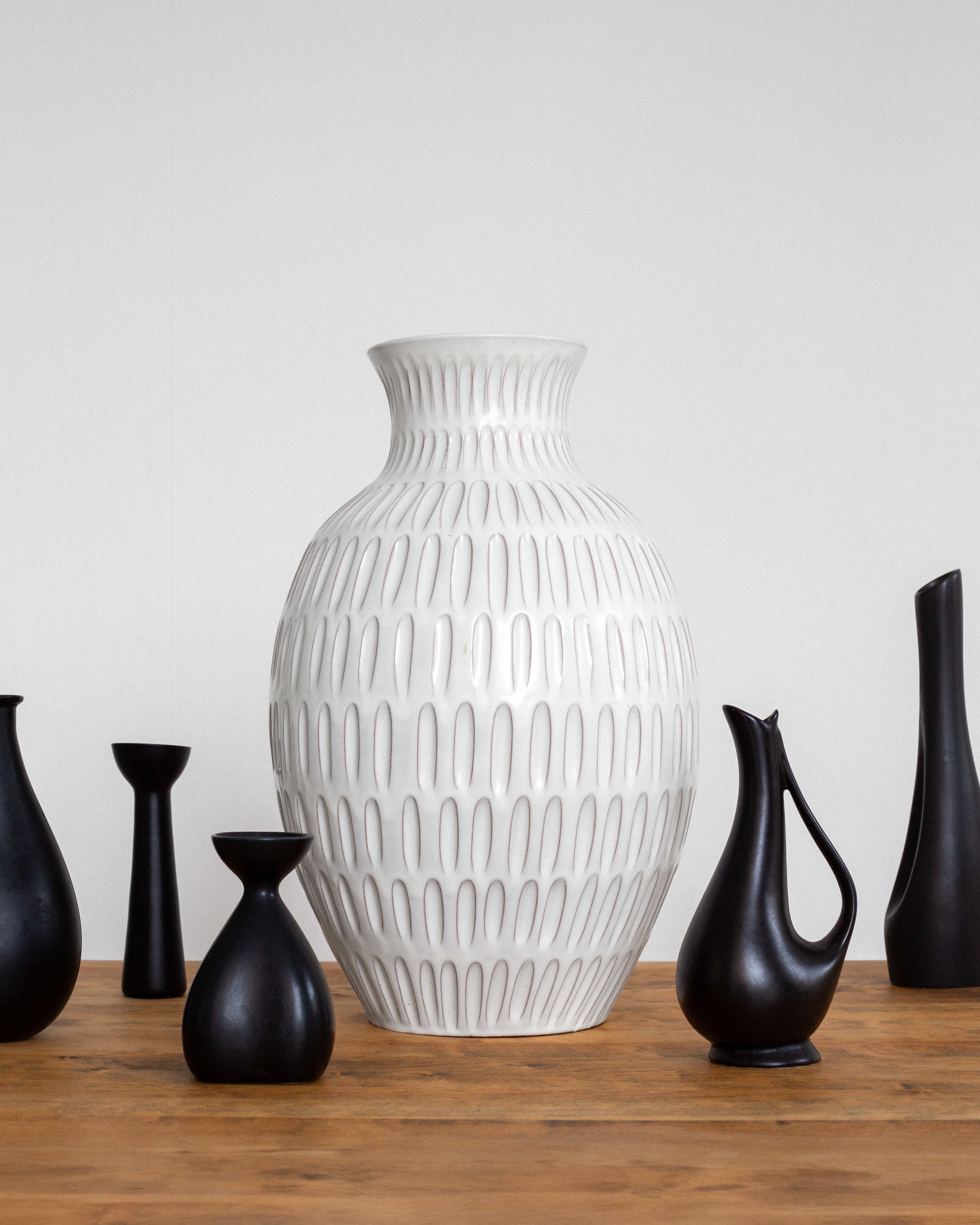 Anna-Lisa Thomson Floor Vase for Upsala-Ekeby, 1940s — white ceramic vase among black vases on wooden table