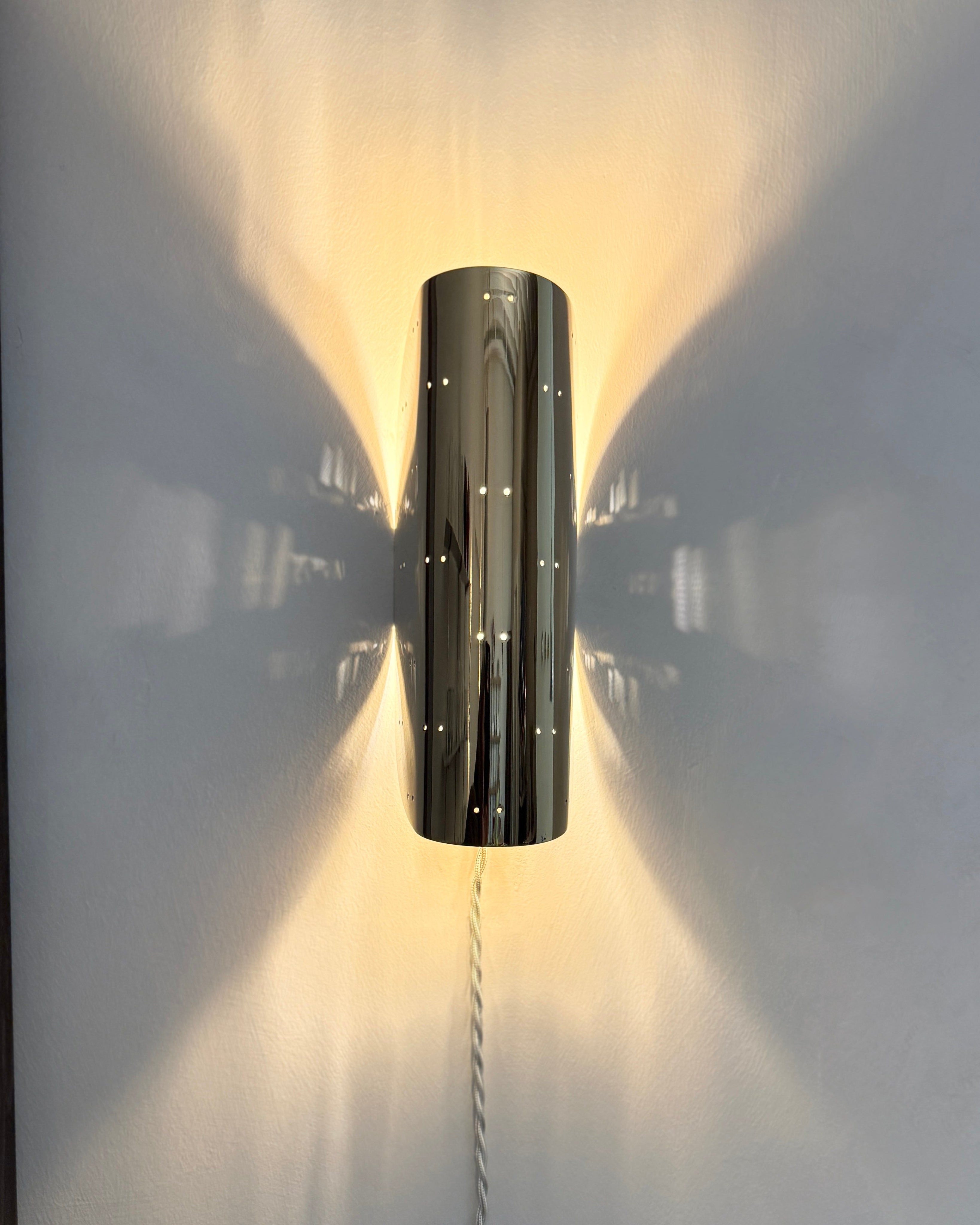 Giselle Wall Lamp - Polished Steel — mounted on wall casting light shadows