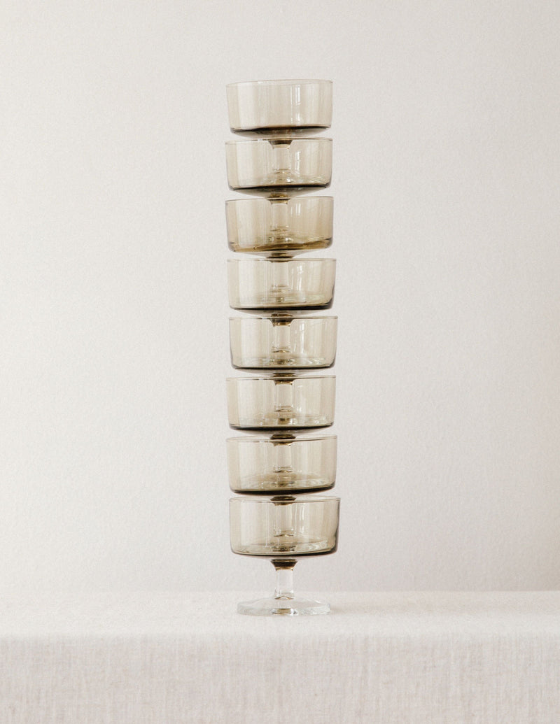 Stack of eight smoked glass champagne coupes with elegant stems