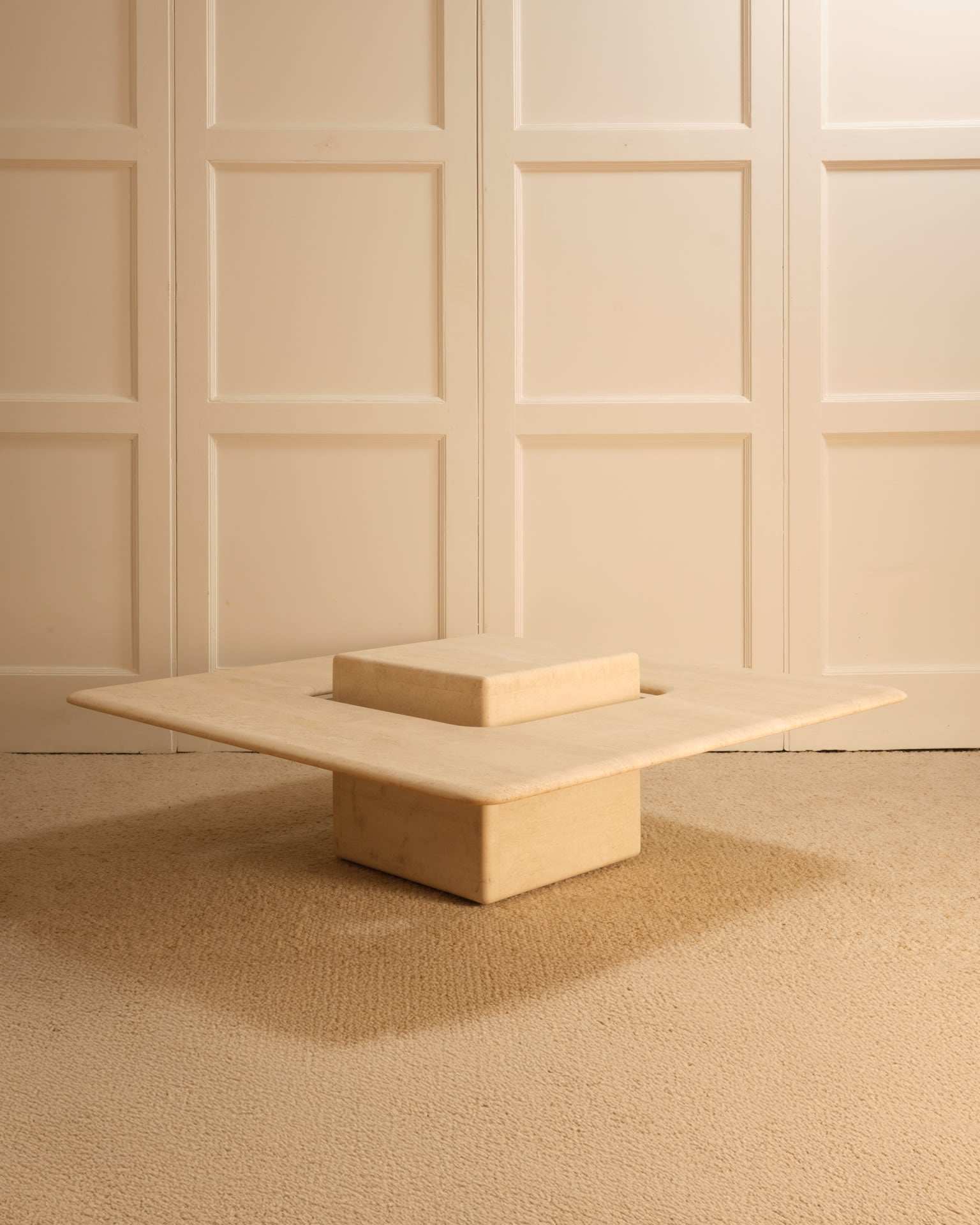 Saturn travertine coffee table with geometric base on textured rug