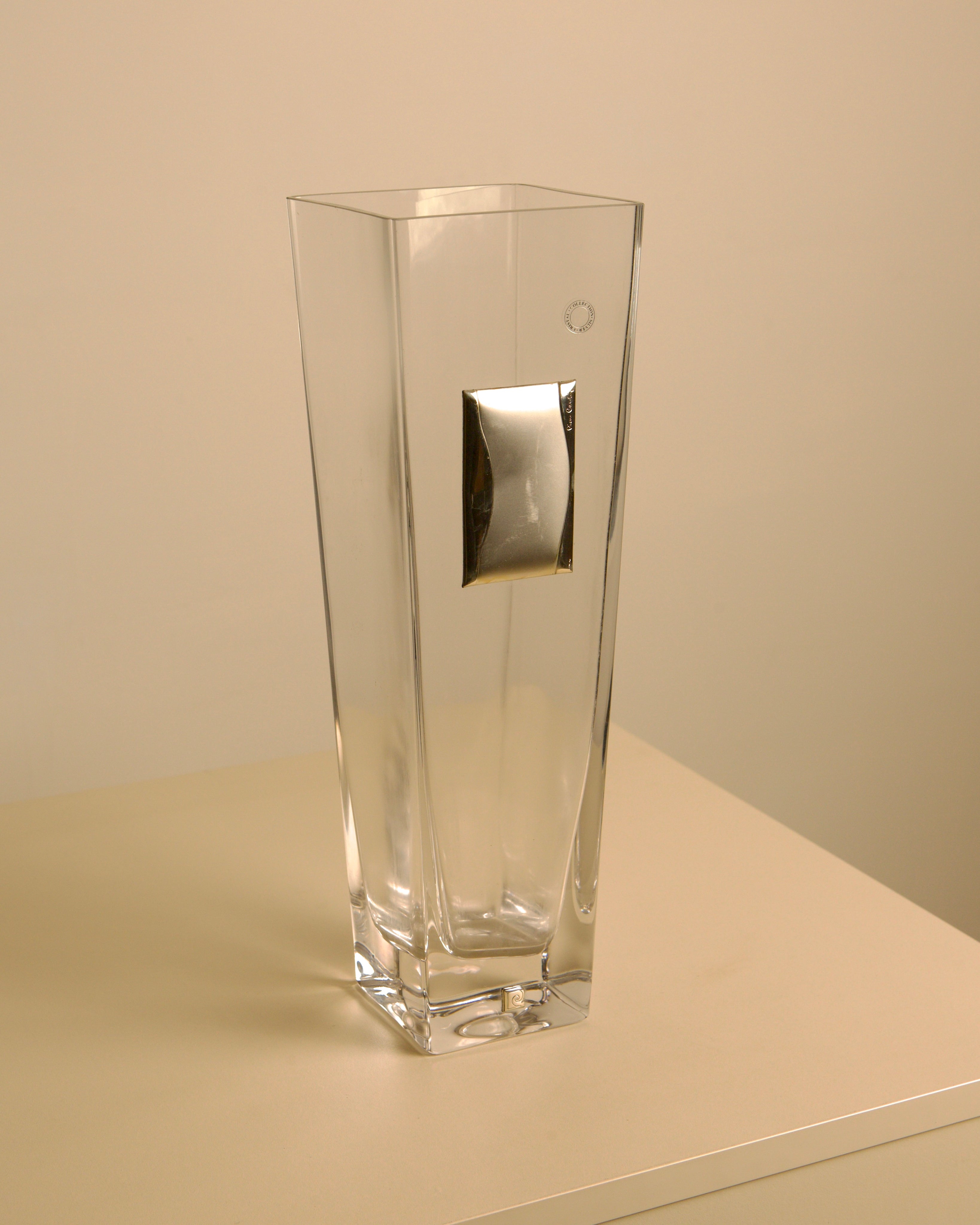 Glass vase with metal details by Pierre Cardin, 1980s — angled view on light-colored surface