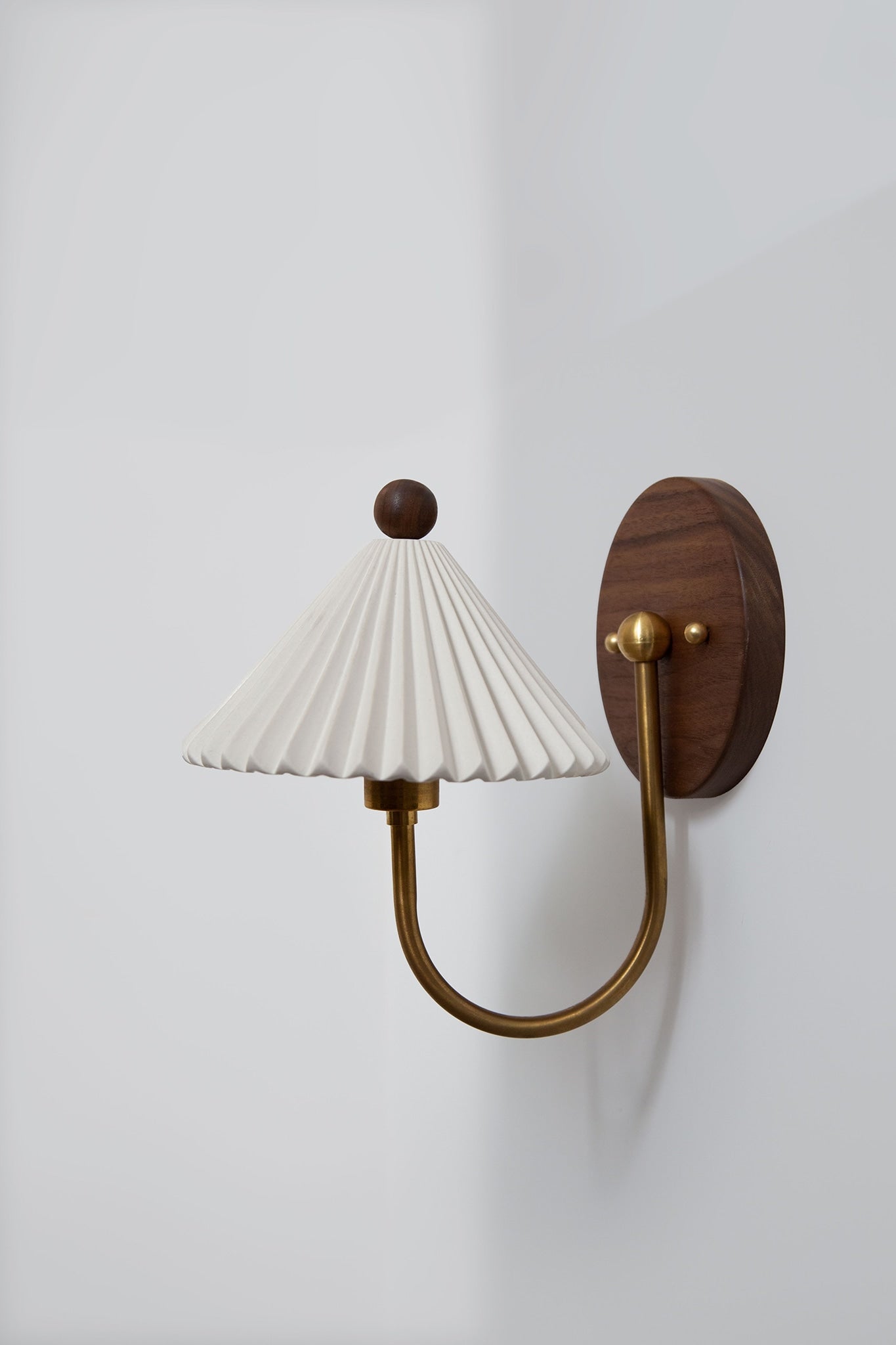Prairie wall sconce with pleated white shade and brass arm detail