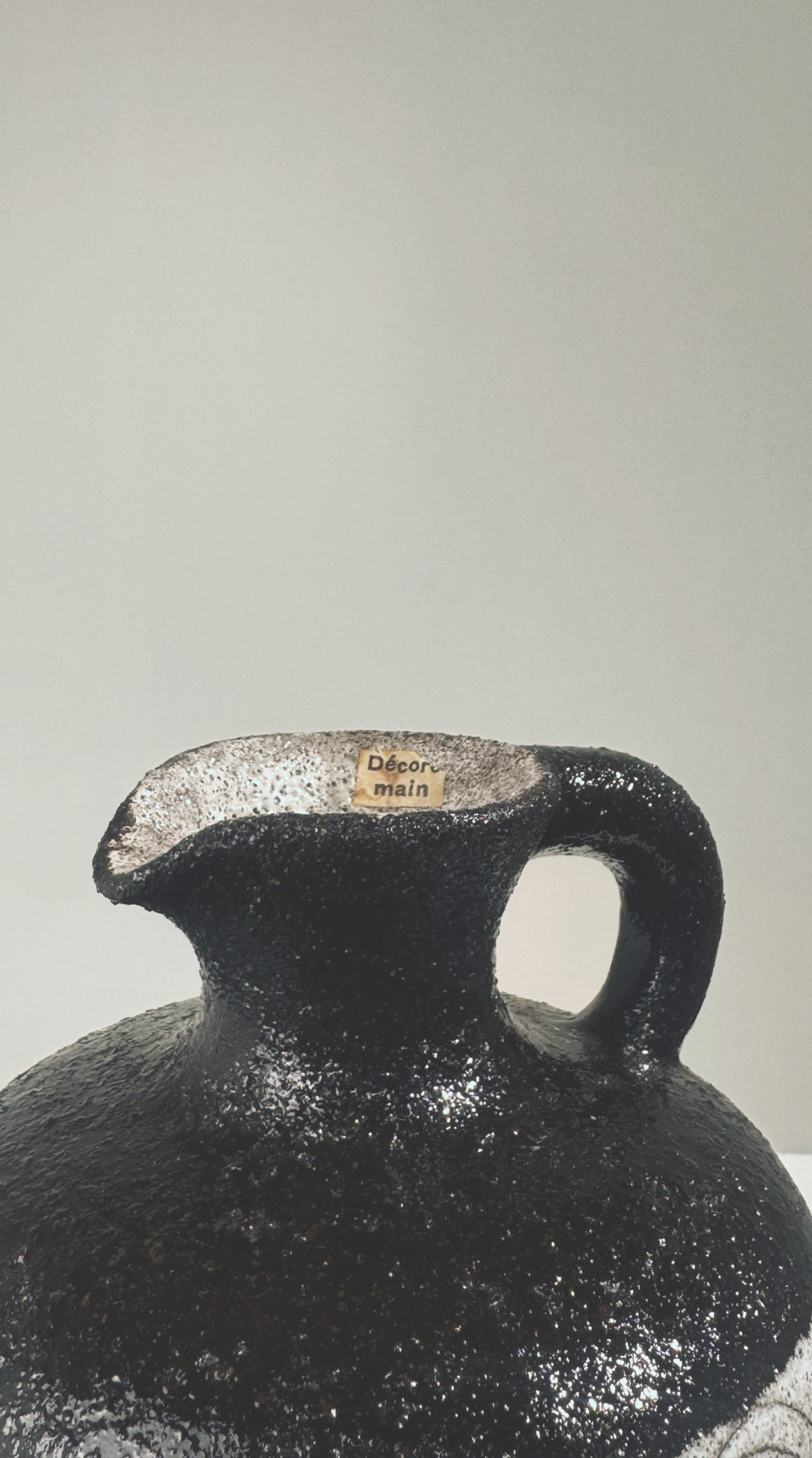 Close-up detail of black textured stoneware pitcher spout and handle