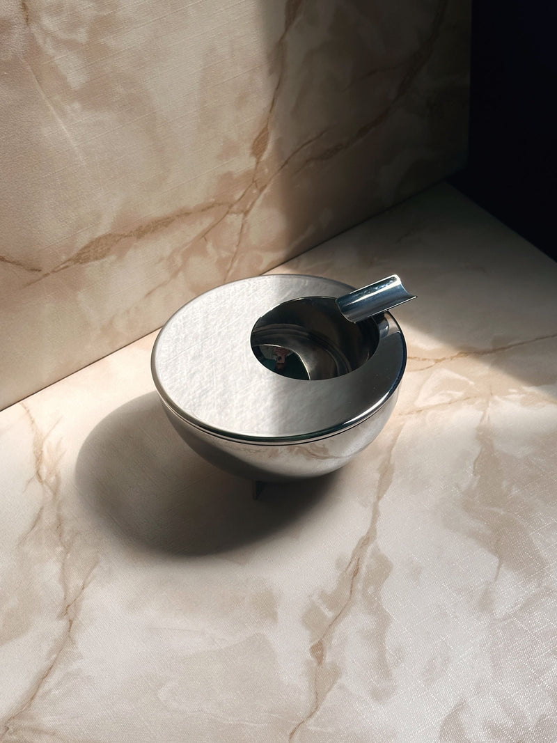 Bauhaus Ashtray by Marianne Brandt by Alessi — close-up of polished metal surface on marble background