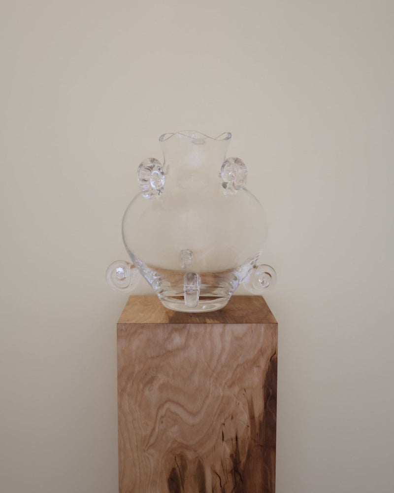 Clear crystal vase with rounded body and ears on wooden pedestal
