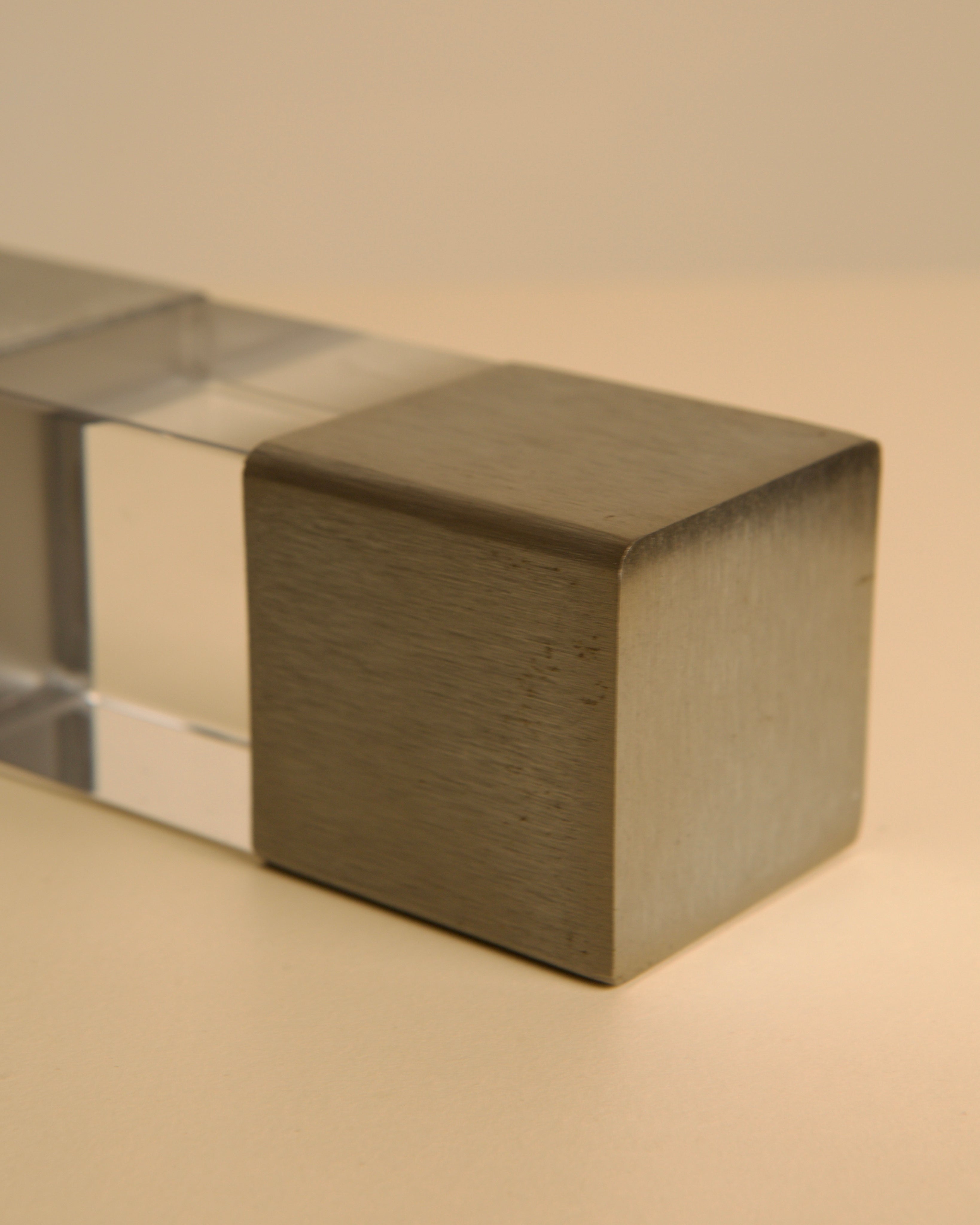 A close-up of the Treaptyque Italian Sculpture in Metal and Plexiglass 70's shows its rectangular form with a clear plexiglass section and brushed metal cube, reflecting iconic 1970s Italian design on a neutral backdrop.