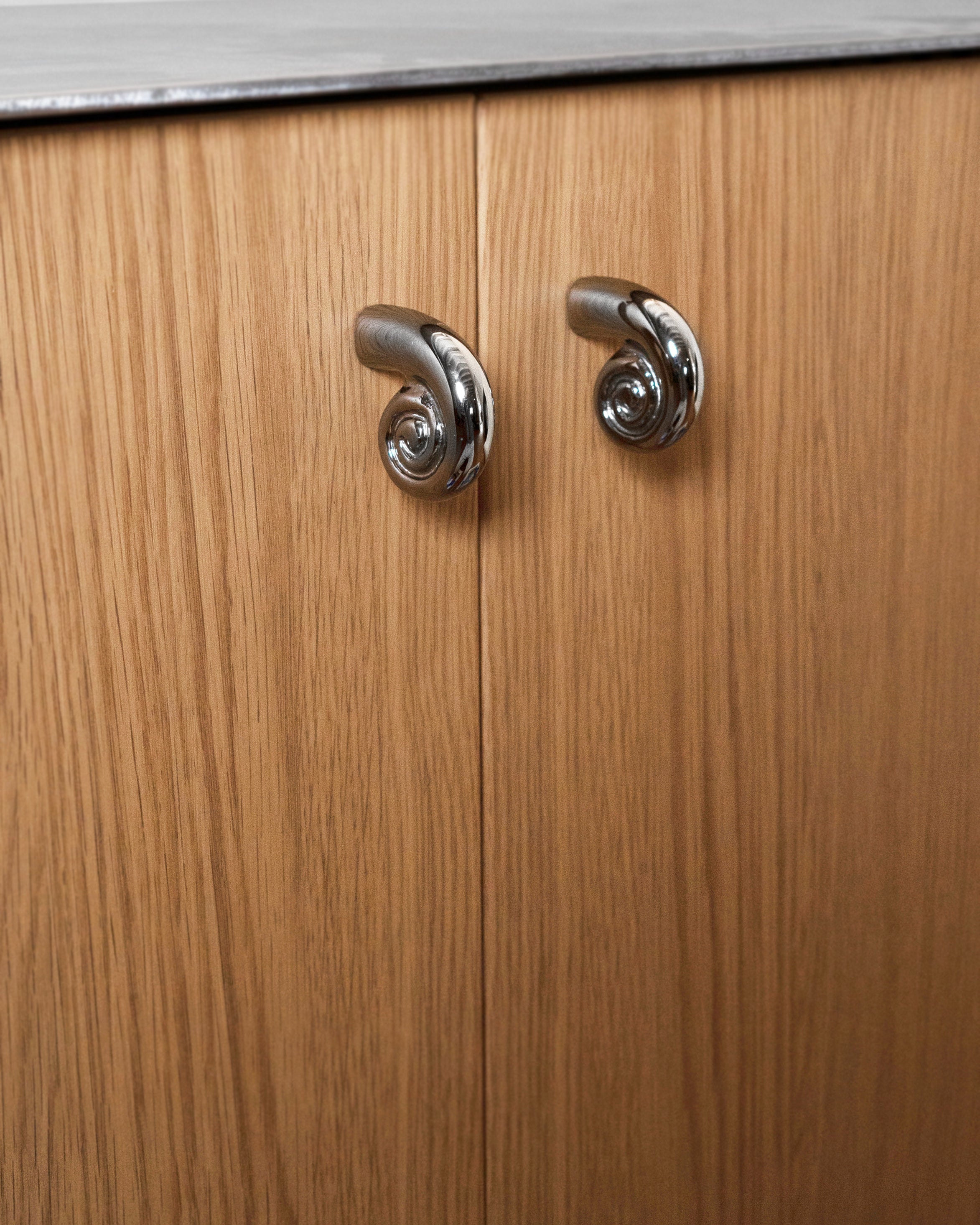 Noelle Knob - Titanium — back view on wooden cabinet doors