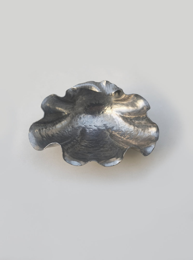 Pewter shell-shaped vide poche with scalloped edges on white background