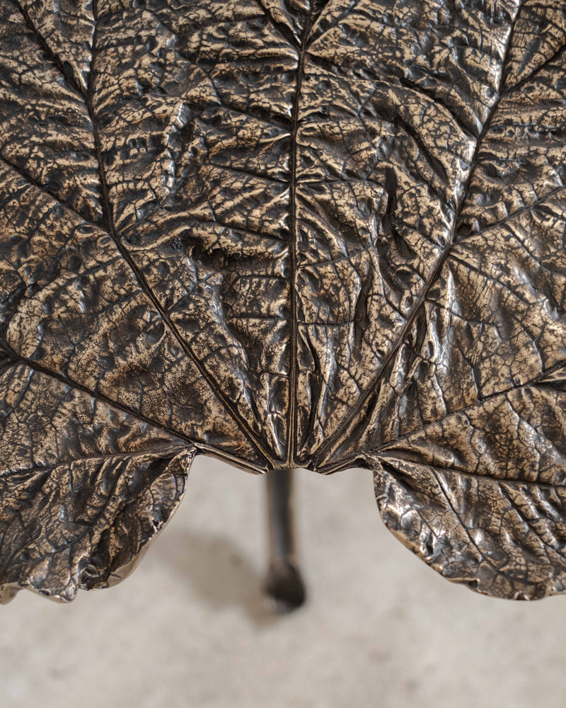 Close-up detail of bronze rhubarb leaves on sculptural side table