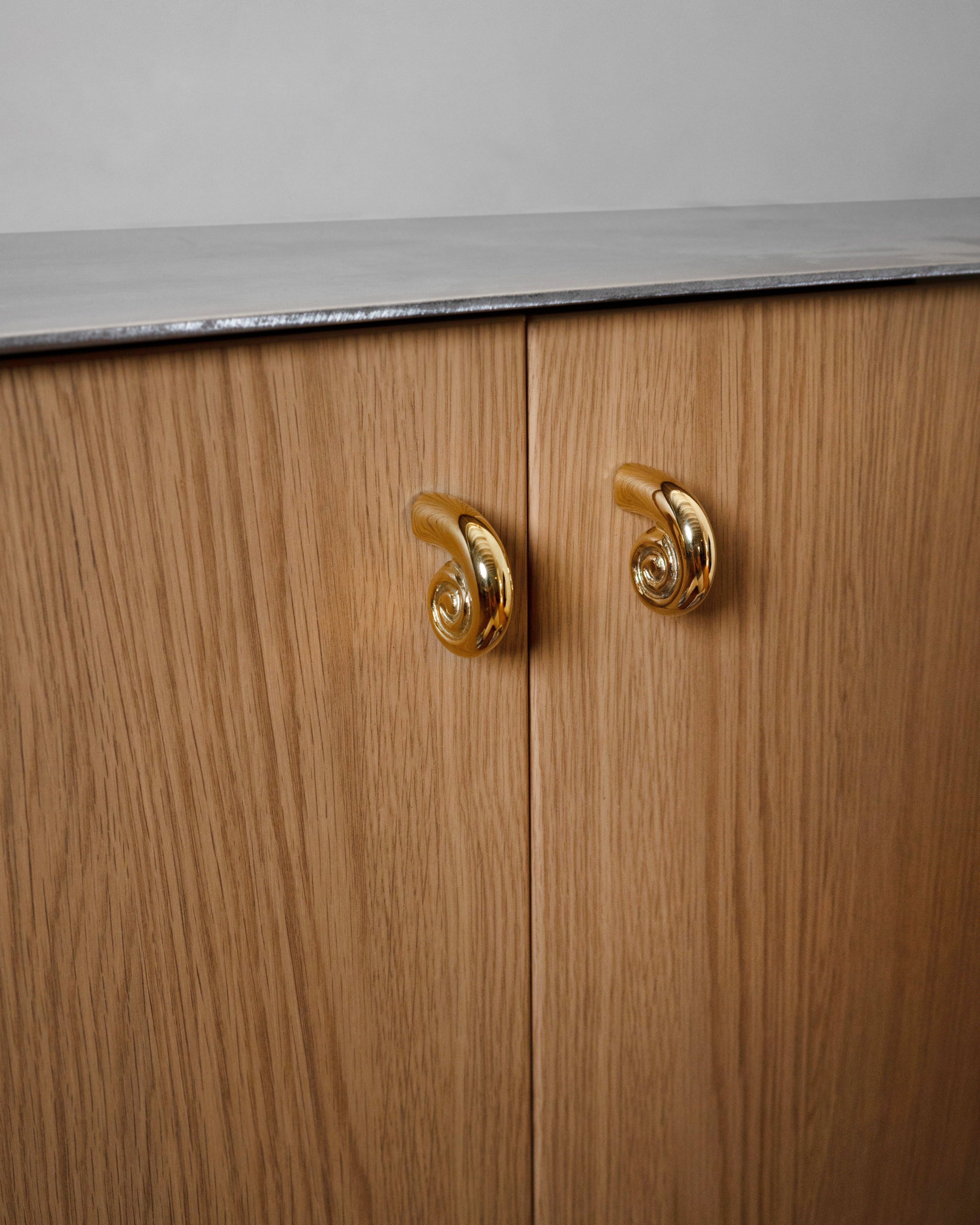 Noelle Knob - Brass — close-up on wooden cabinet doors with brass knobs
