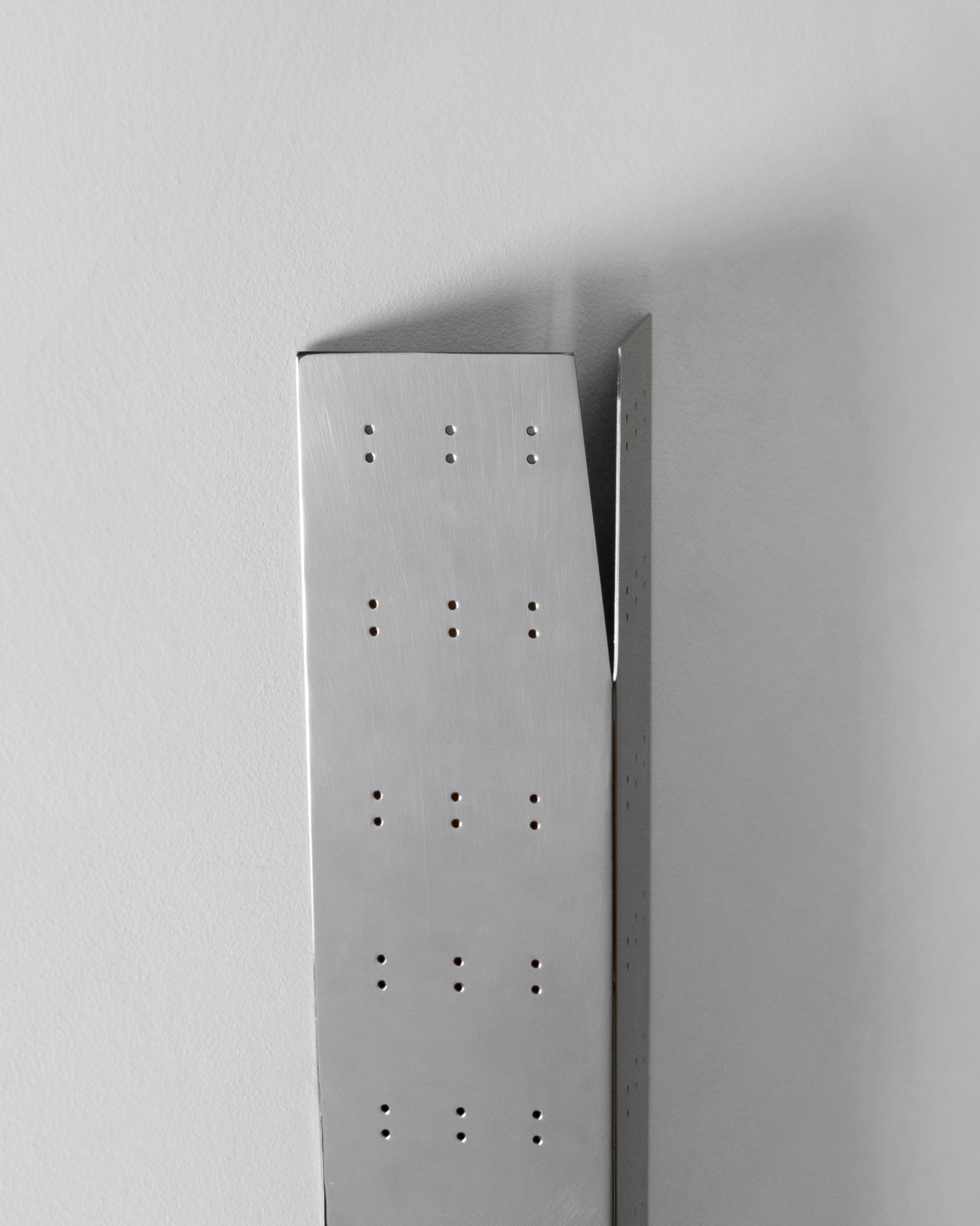 May Wall Lamp - Polished Steel — angled view against white wall
