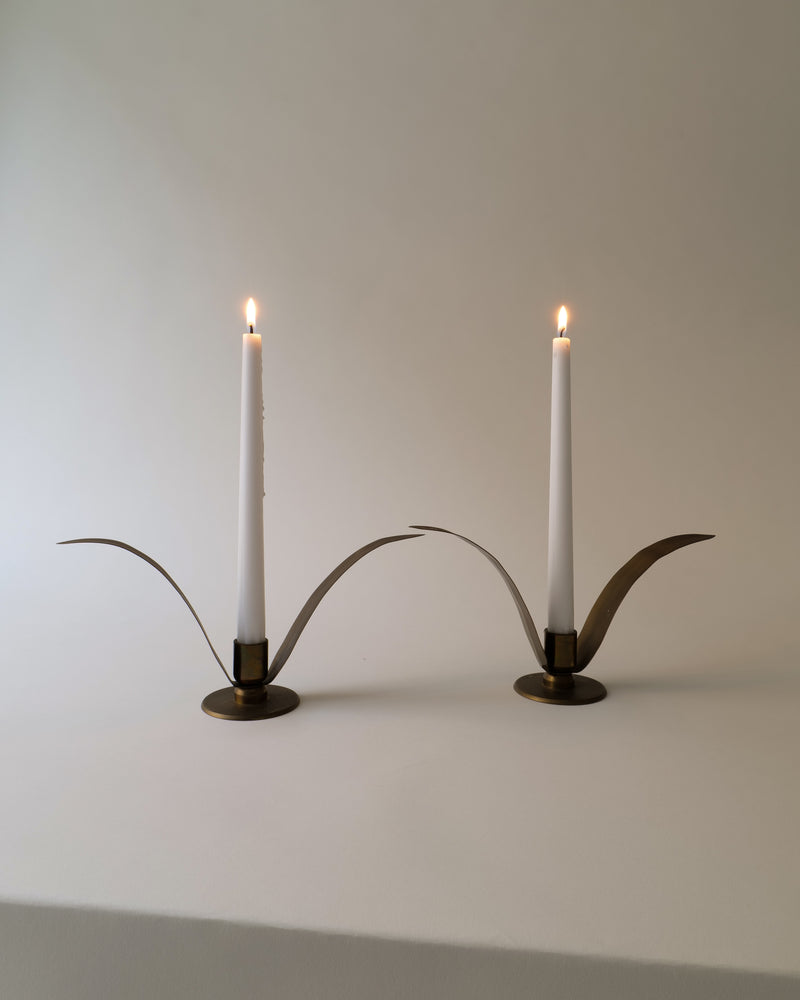 Liljan brass candle holders with curved handles and lit white candles