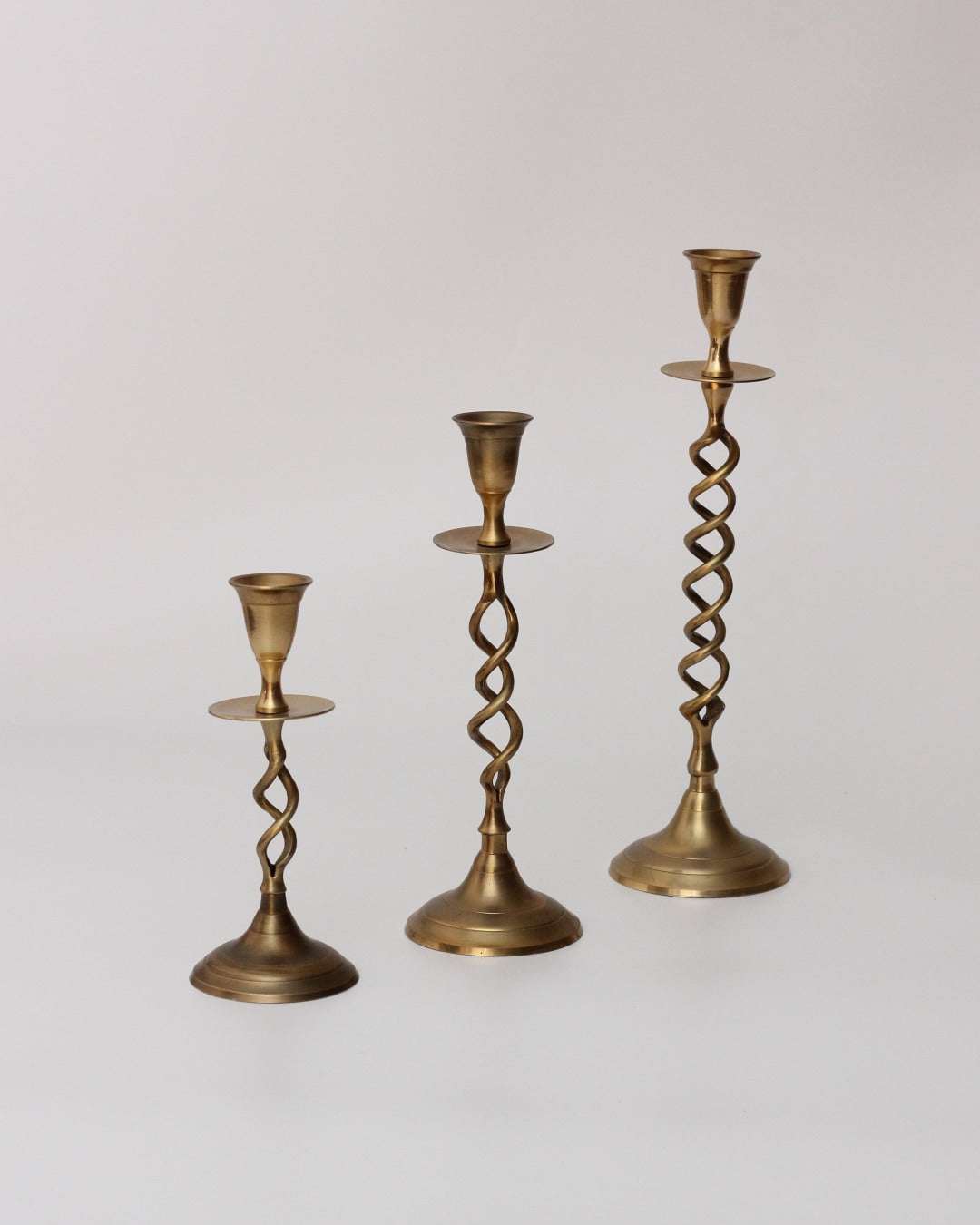 Trio Candelabros Latón — side view of twisted brass candle holders