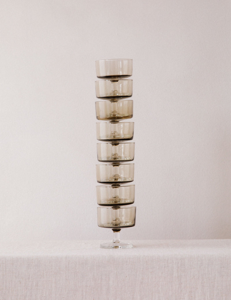 Stack of eight smoked glass champagne coupes arranged vertically