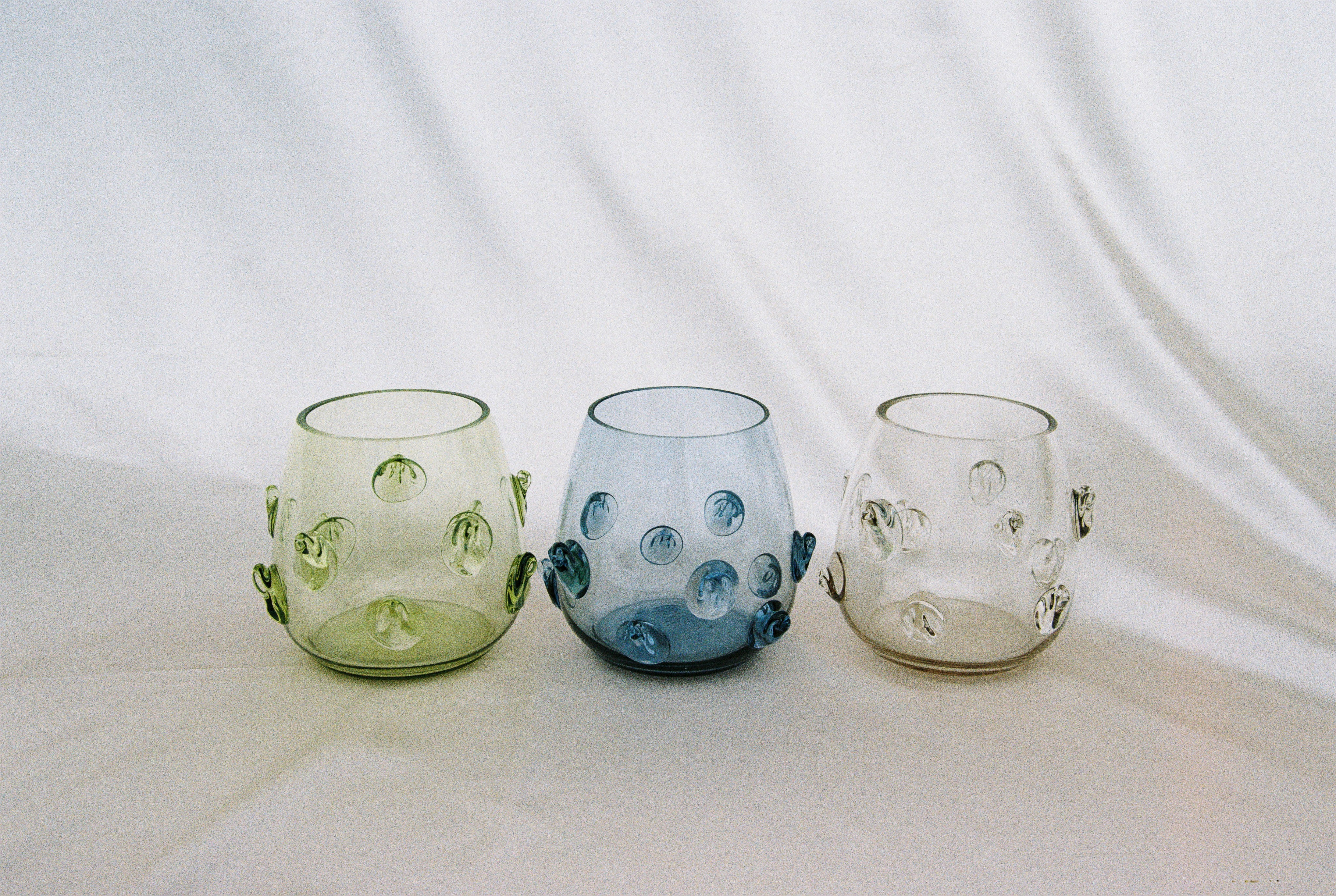 Contemporary Tumblr - Set of four handblown glass vessels — angled view on soft fabric background