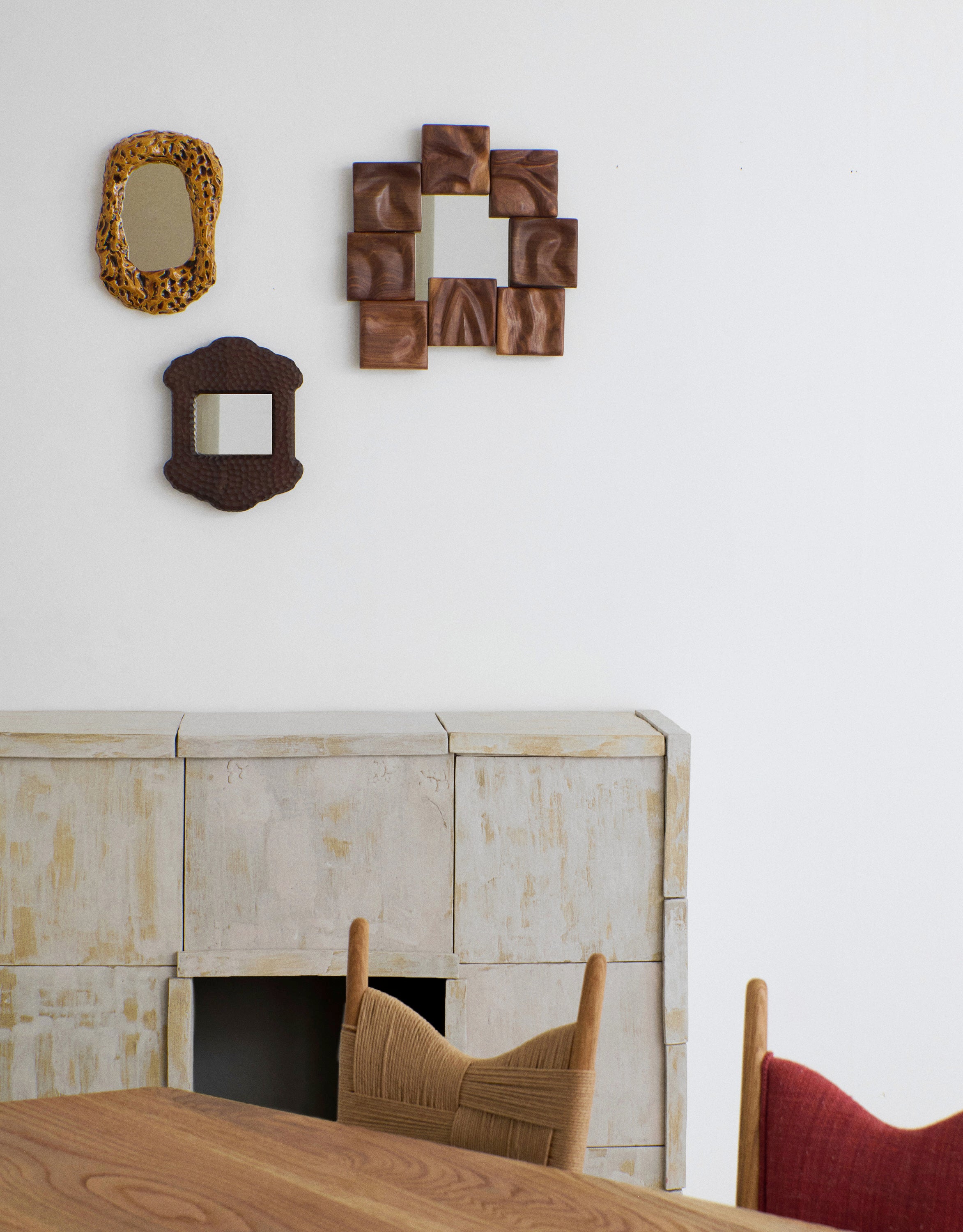 Small Catarina Mirror — side angle on textured wall above wooden console