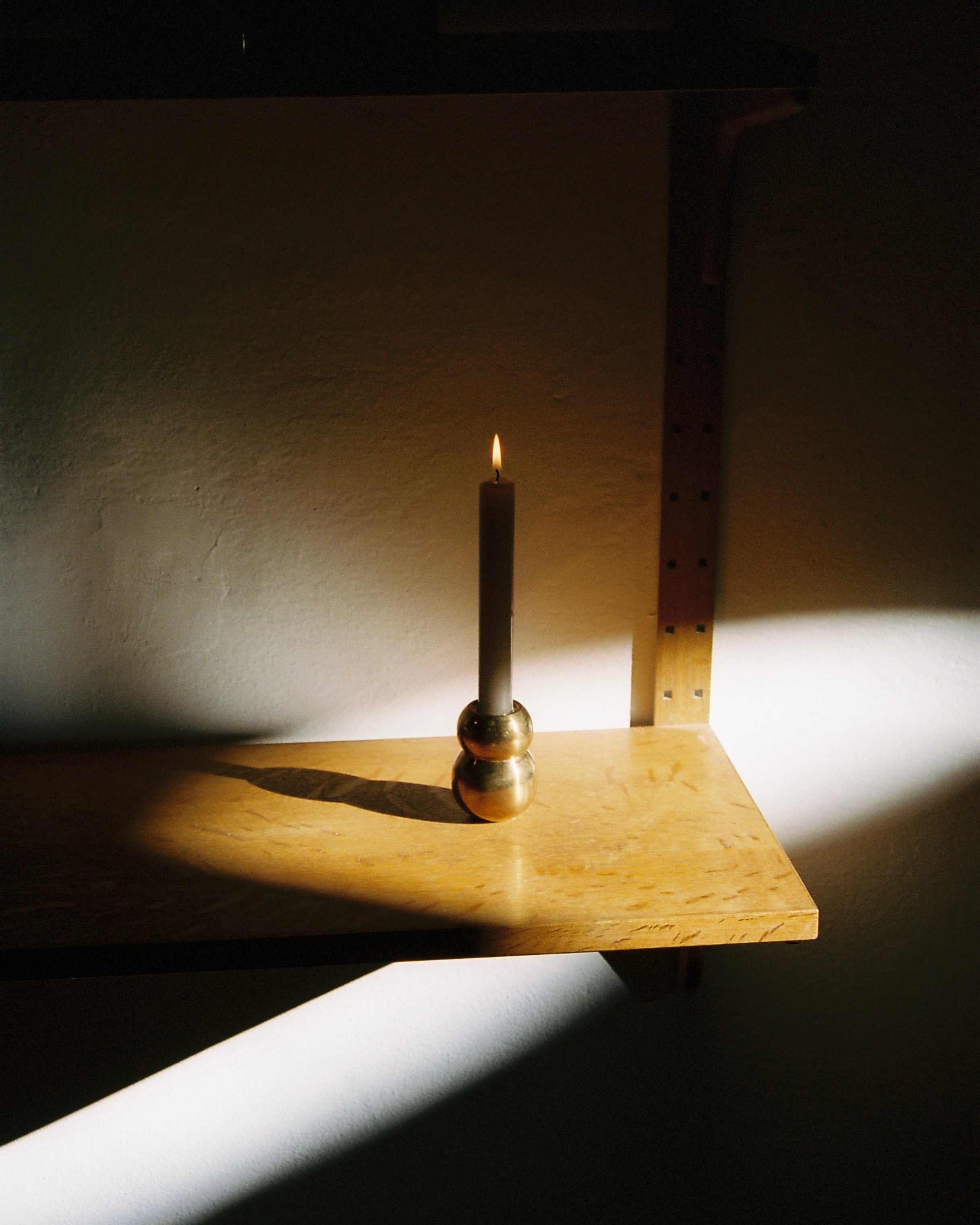 ANJOU Candleholder — close-up of brass holder with candle on wooden shelf