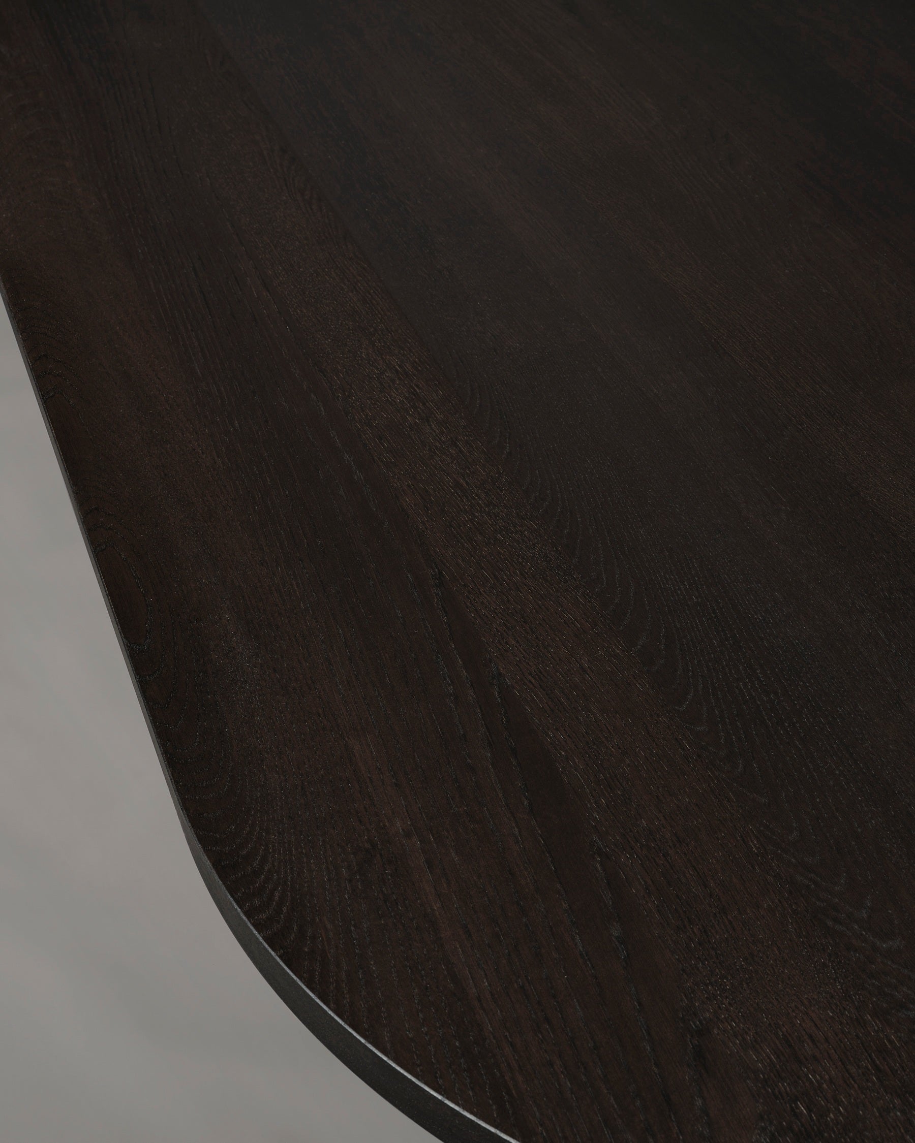 A close-up of the Mokko Acer Capsule Table showcases its solid European oak construction, smooth rounded edge, and visible wood grain set against a light background.