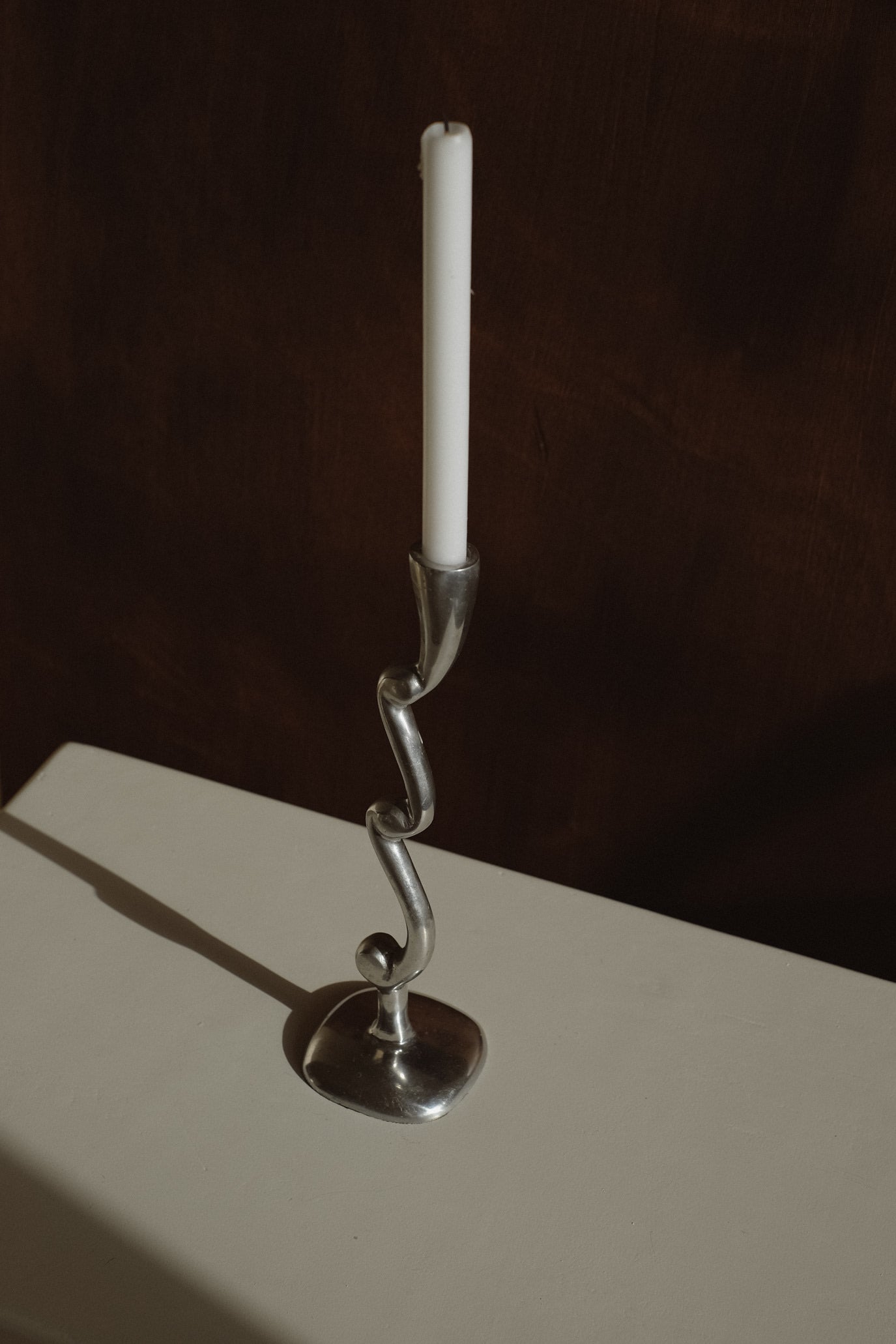 Curly Candle Holder — angled view on white surface with silver finish