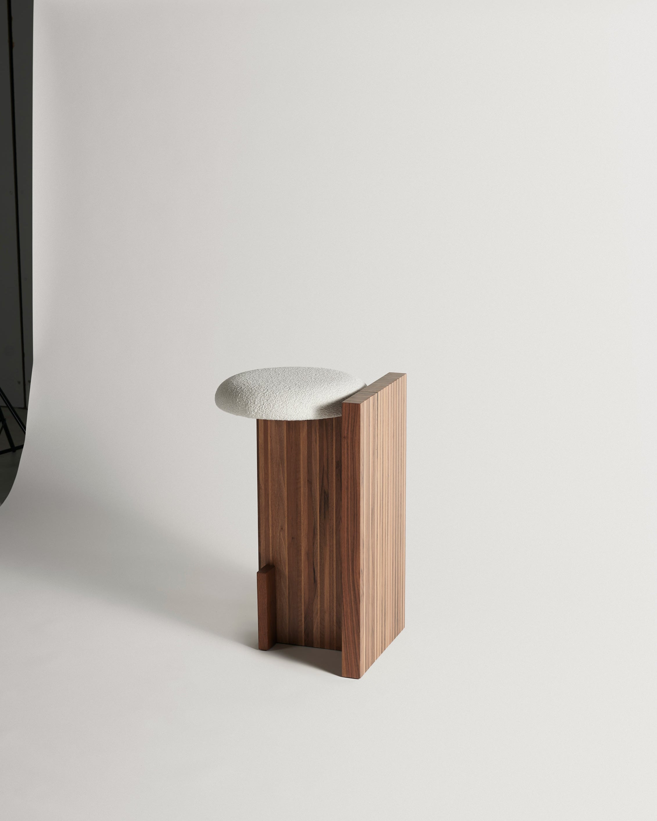 Arquivo Counter Stool — side angle showing walnut base and upholstered seat