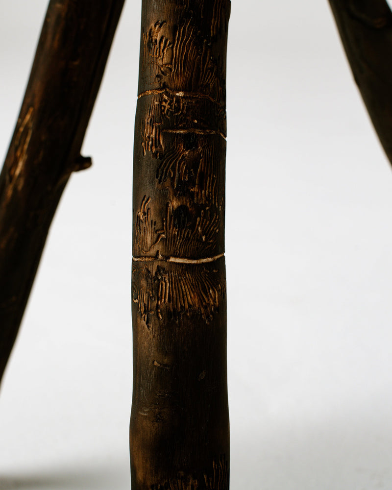 Carved detail of burned wood stool with decorative branch motifs