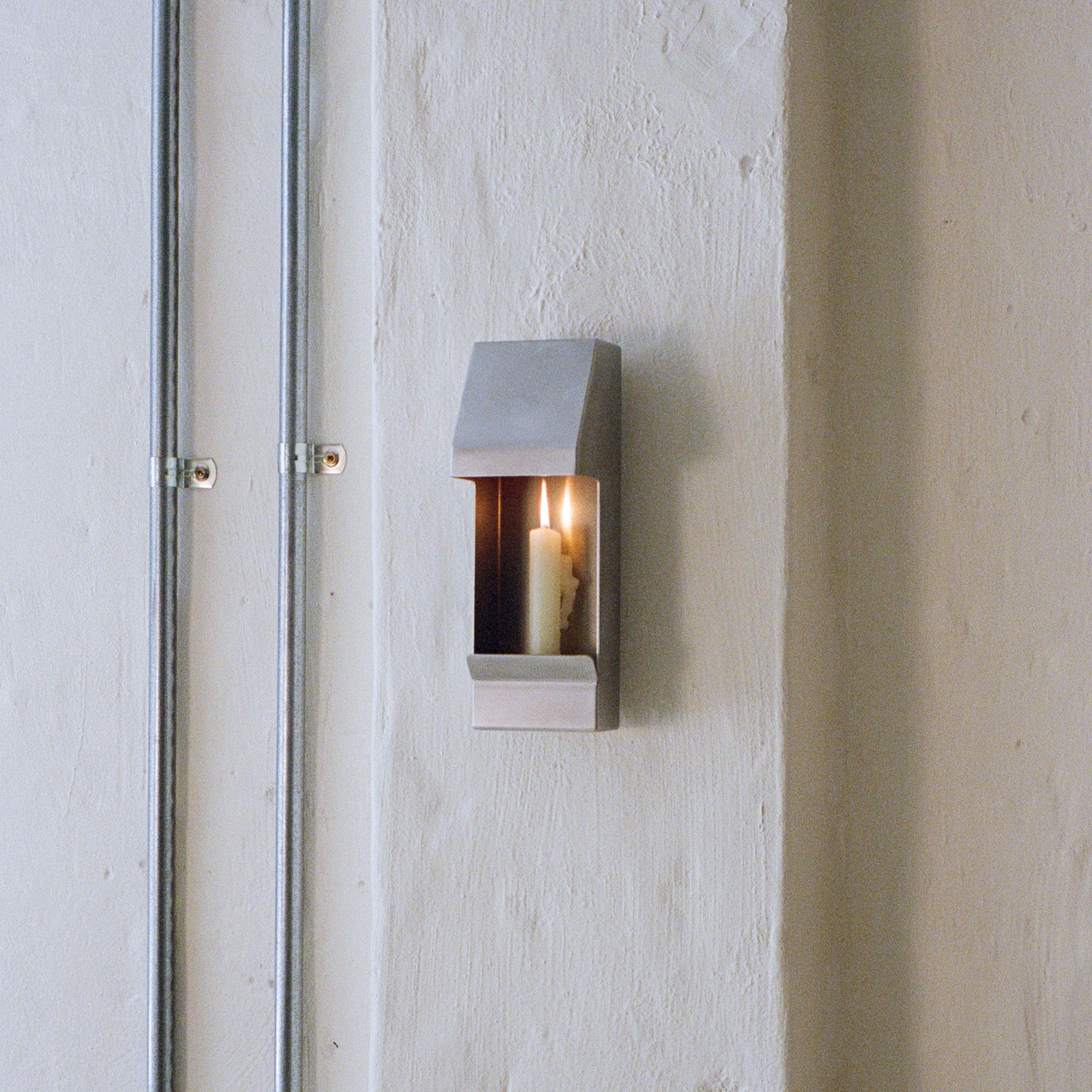 Egress Sconce Candle Holder — wall-mounted with lit candle in modern setting