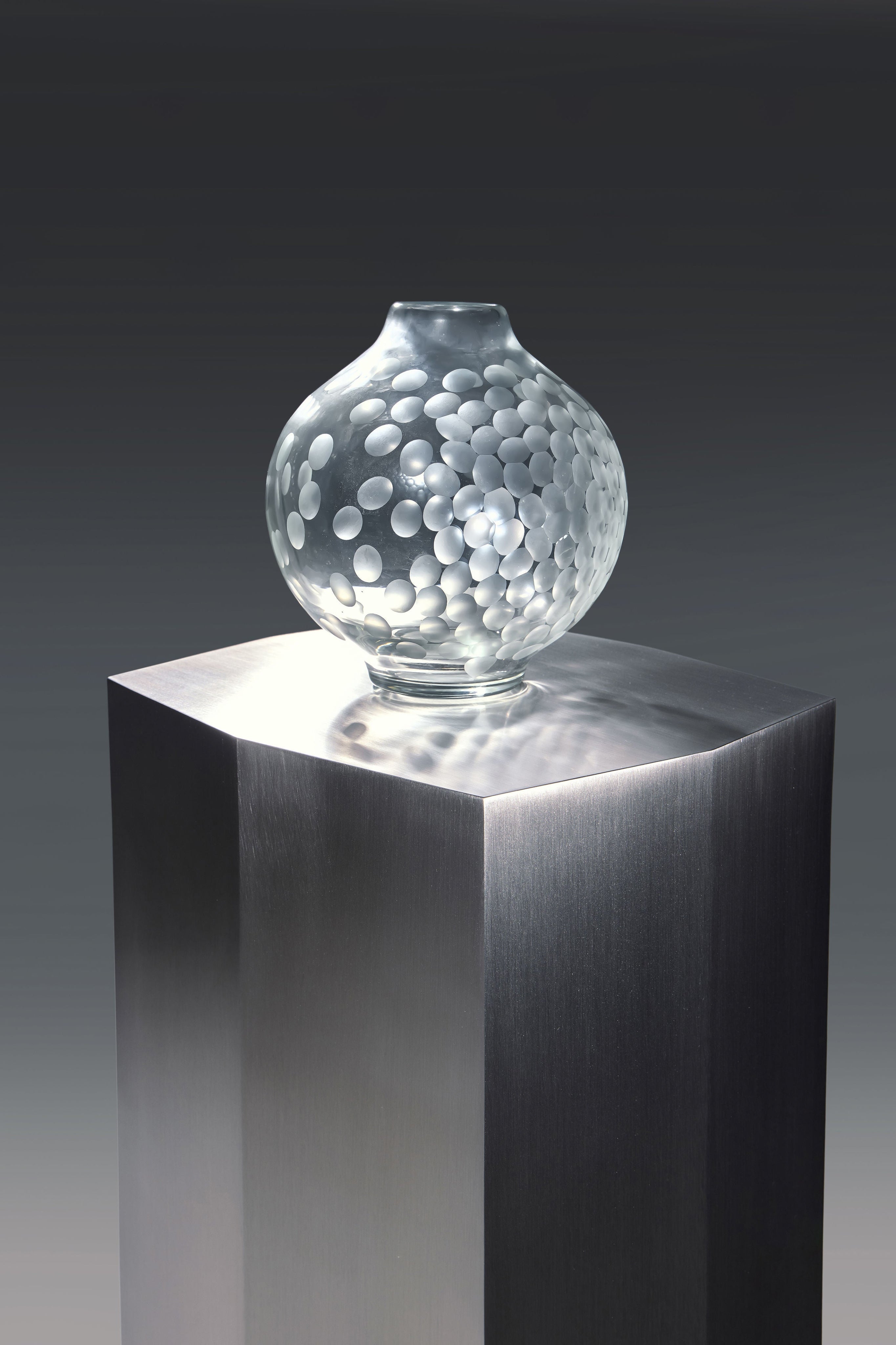 Ame II' Steel Pedestal — close-up of polished steel surface with glass vase