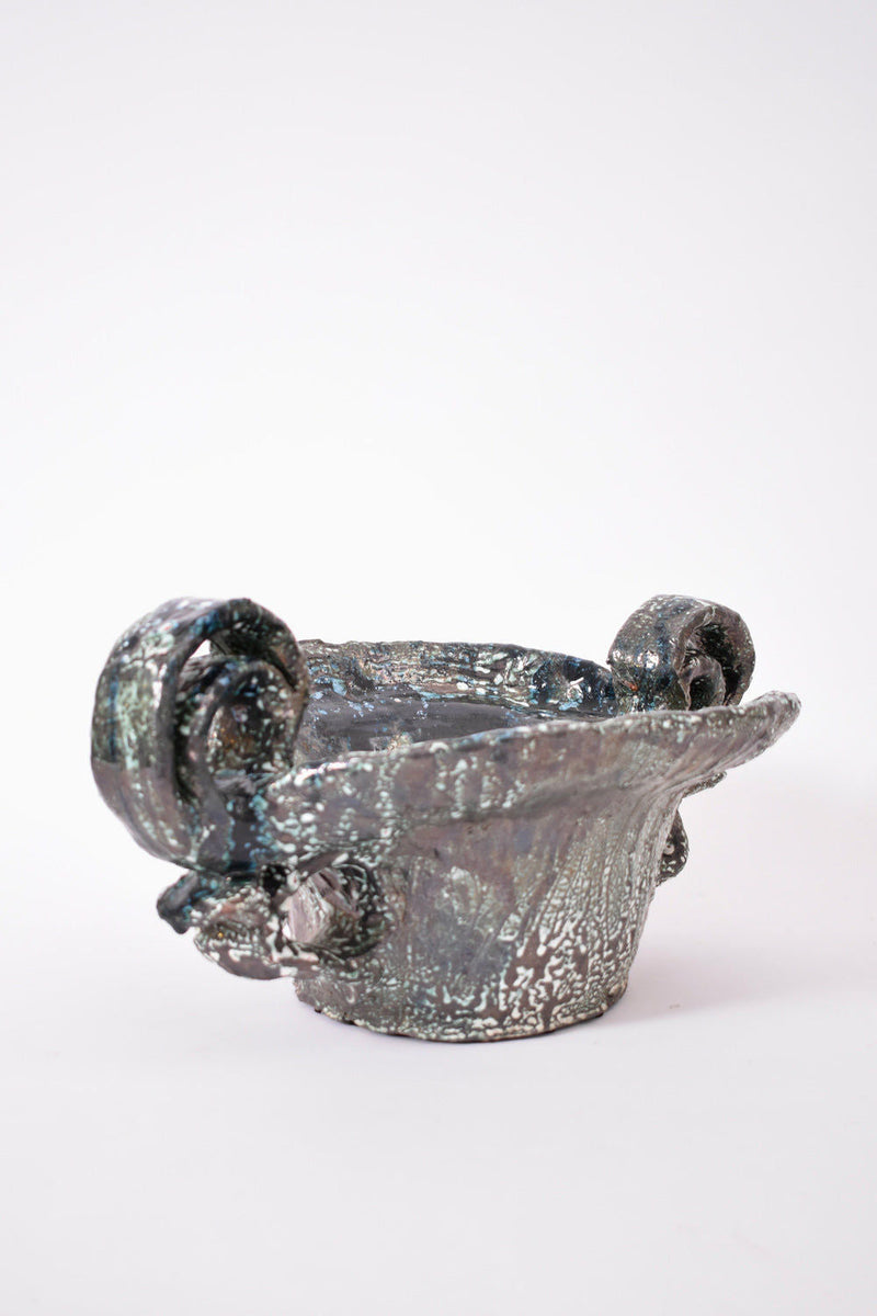 The Helder Handles Large Ceramic Bowl, 2025 by Barracuda Interiors features a textured metallic finish and two ornate curled handles, displayed against a plain white background.