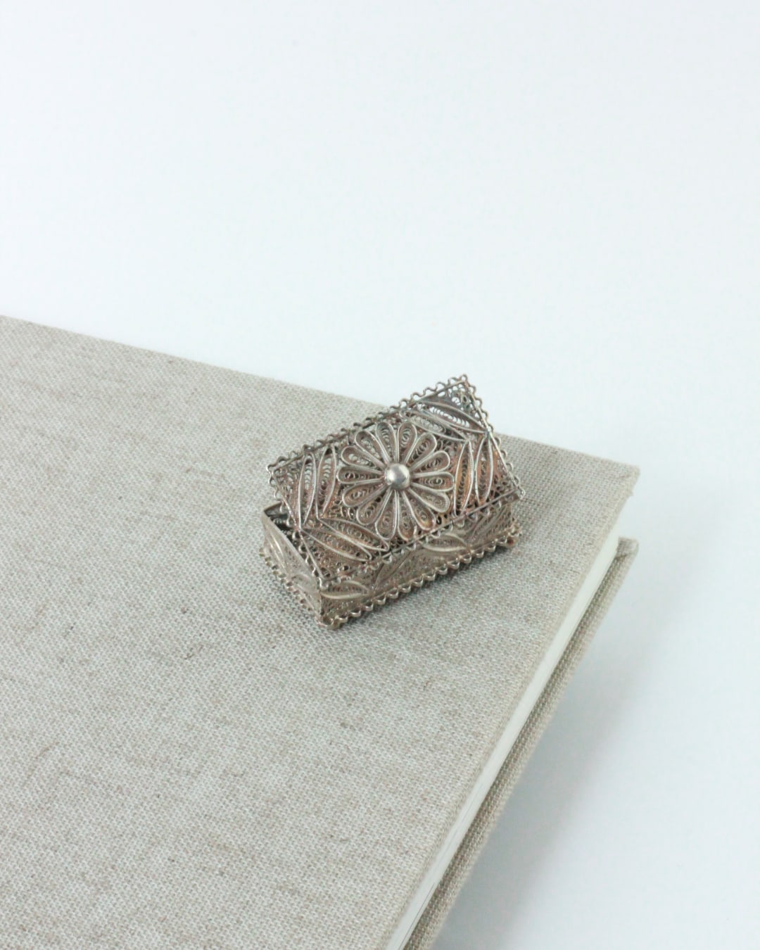 Silver Pillbox — placed on textured linen notebook