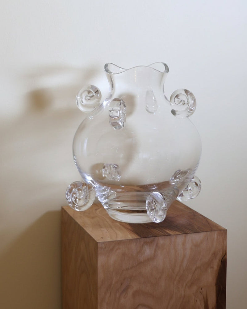 Clear crystal vase with curved handles on wooden display stand