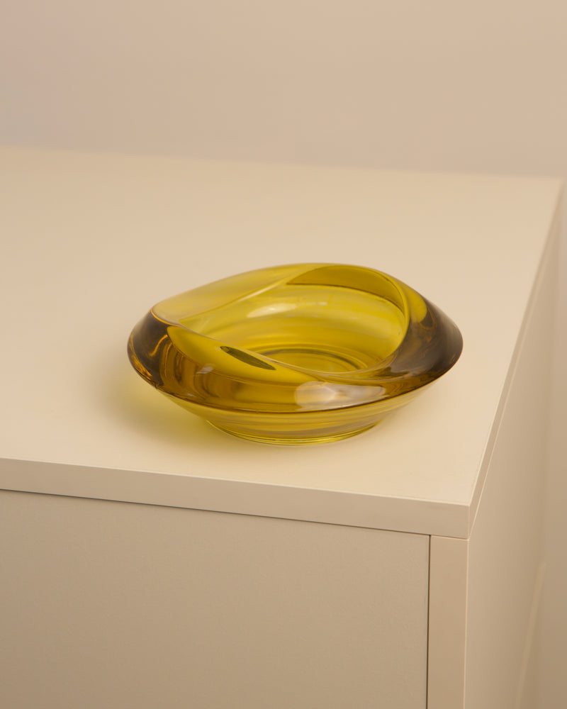 Amber yellow Murano glass bowl on minimalist white shelf