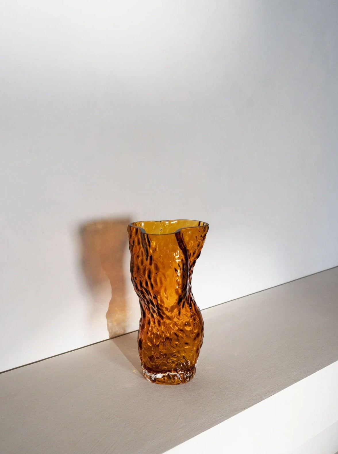 Ostrea Rock Glass Vase - Amber — angled view on light wooden shelf