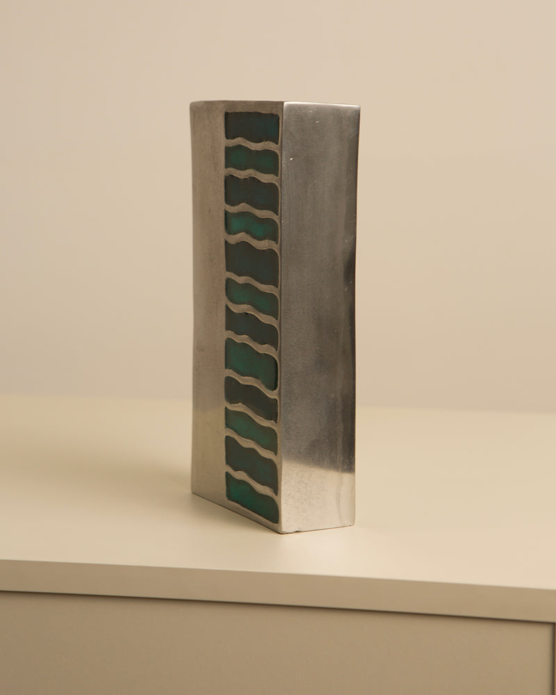 Profile view of green enameled aluminum vase with wavy cutout pattern