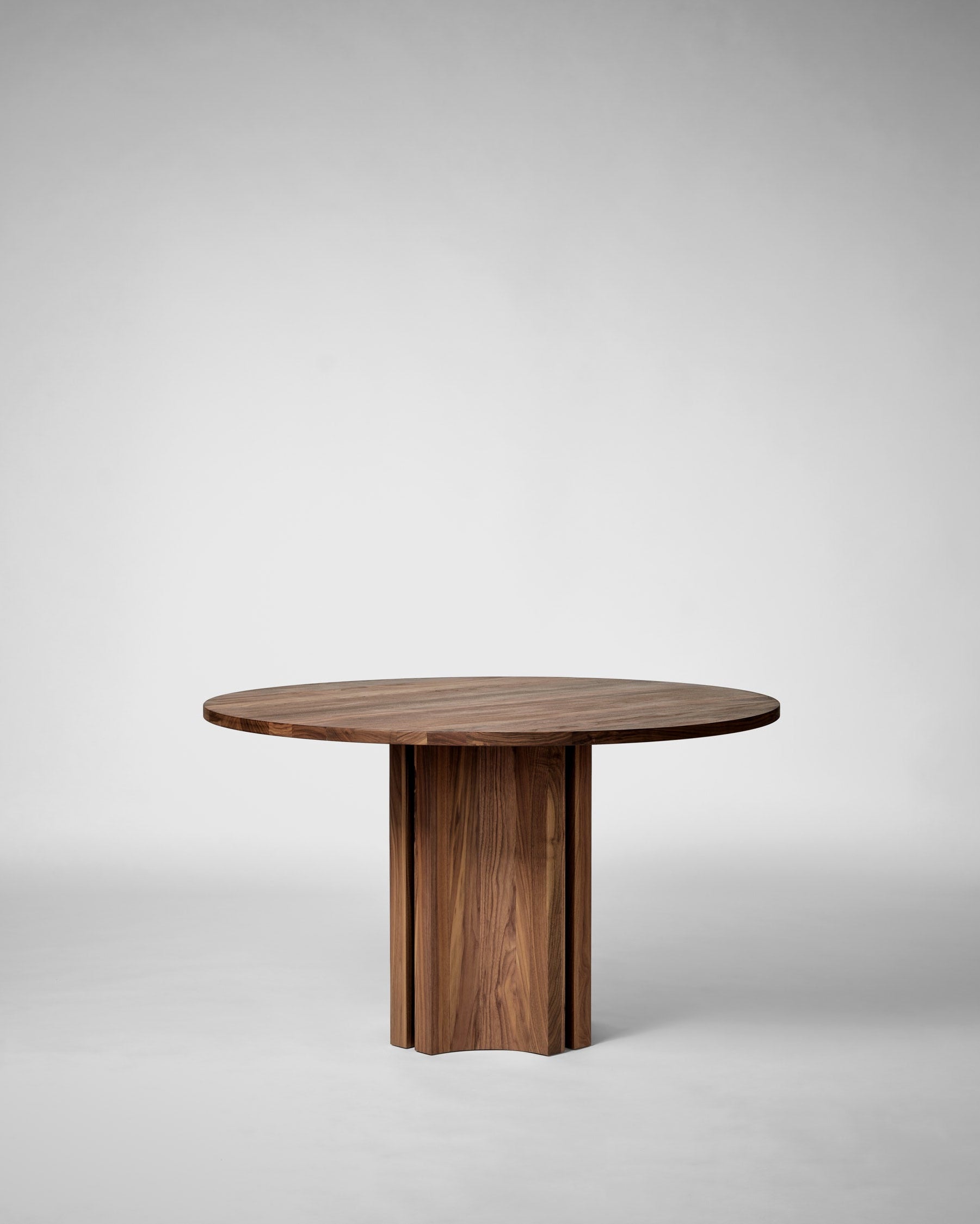 Round walnut dining table with cylindrical pedestal base by Mokko